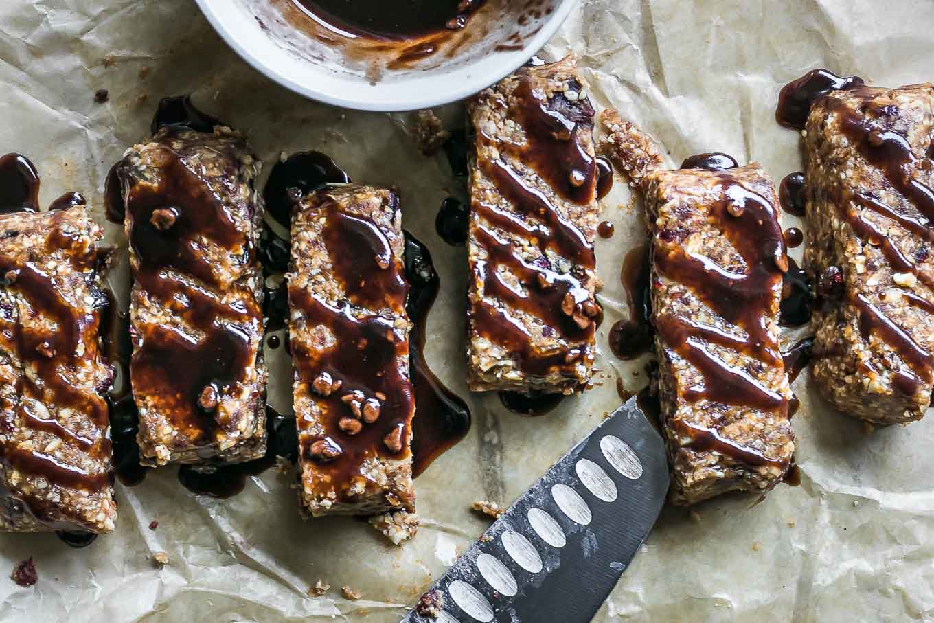 homemade peanut butter granola bars with chocolate drizzled on top on parchment paper