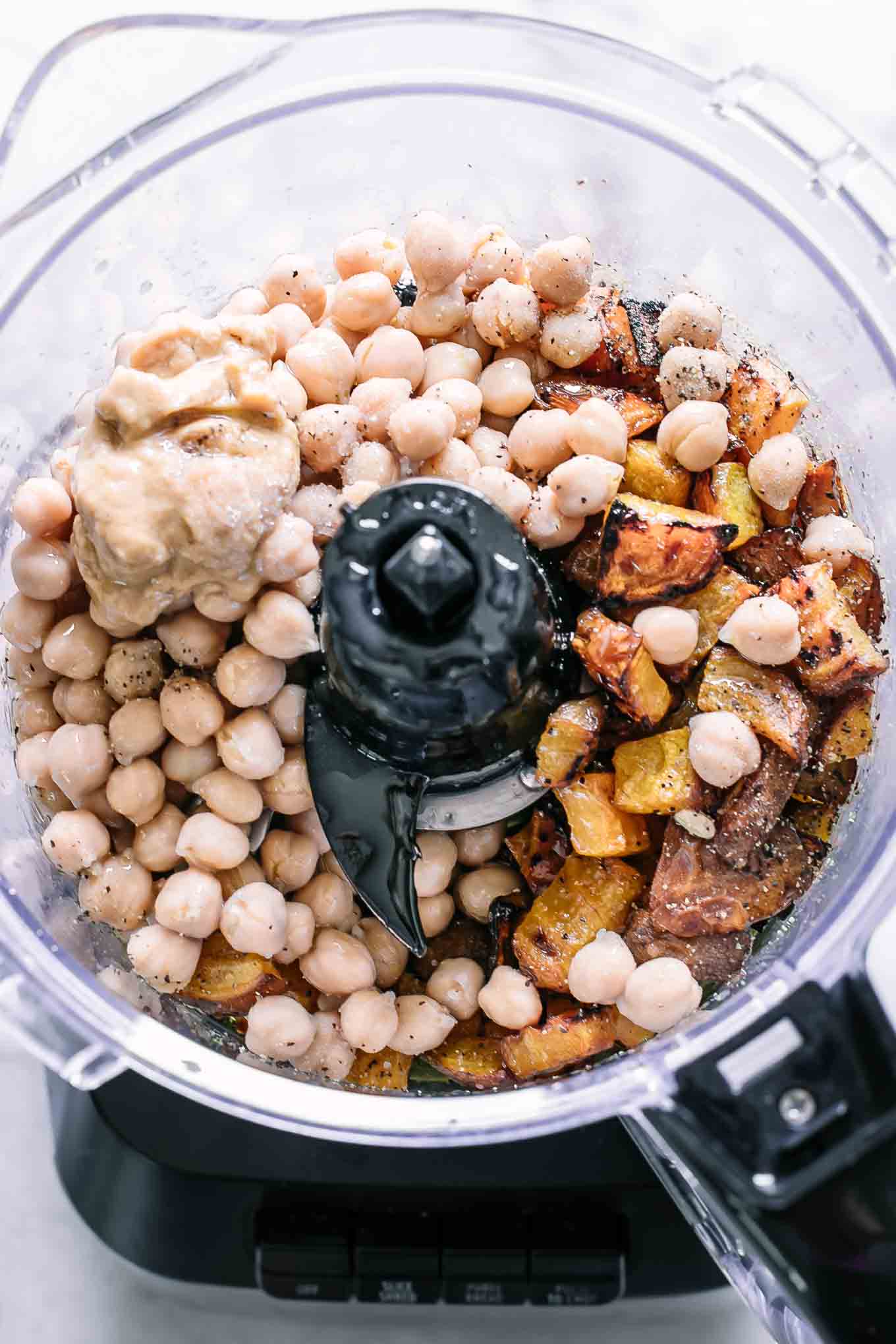 a food processor with chickpeas, roasted golden beets, tahini, oil, garlic, salt and pepper  before blending