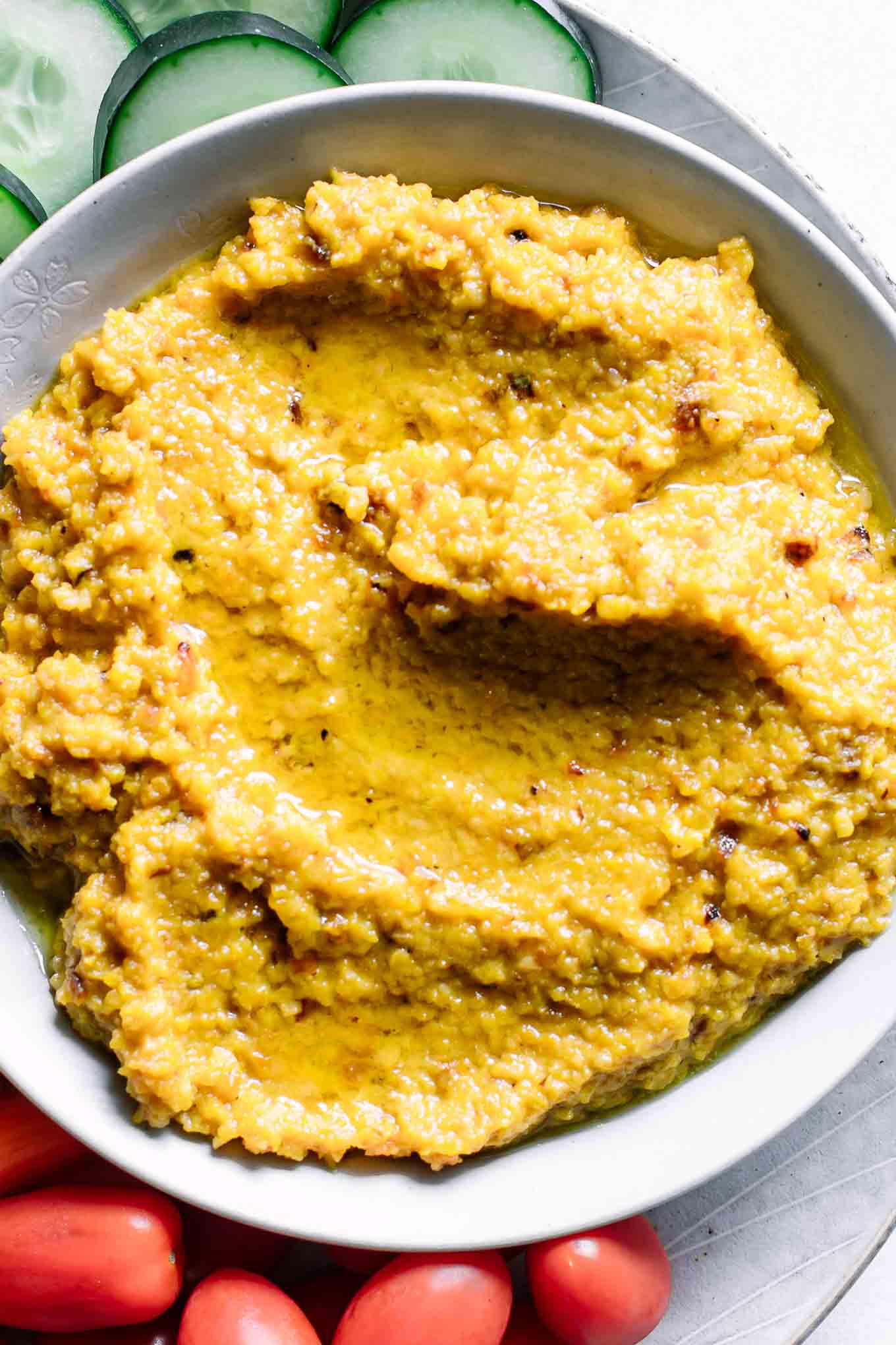a close up photo of hummus made with golden beets in a bowl