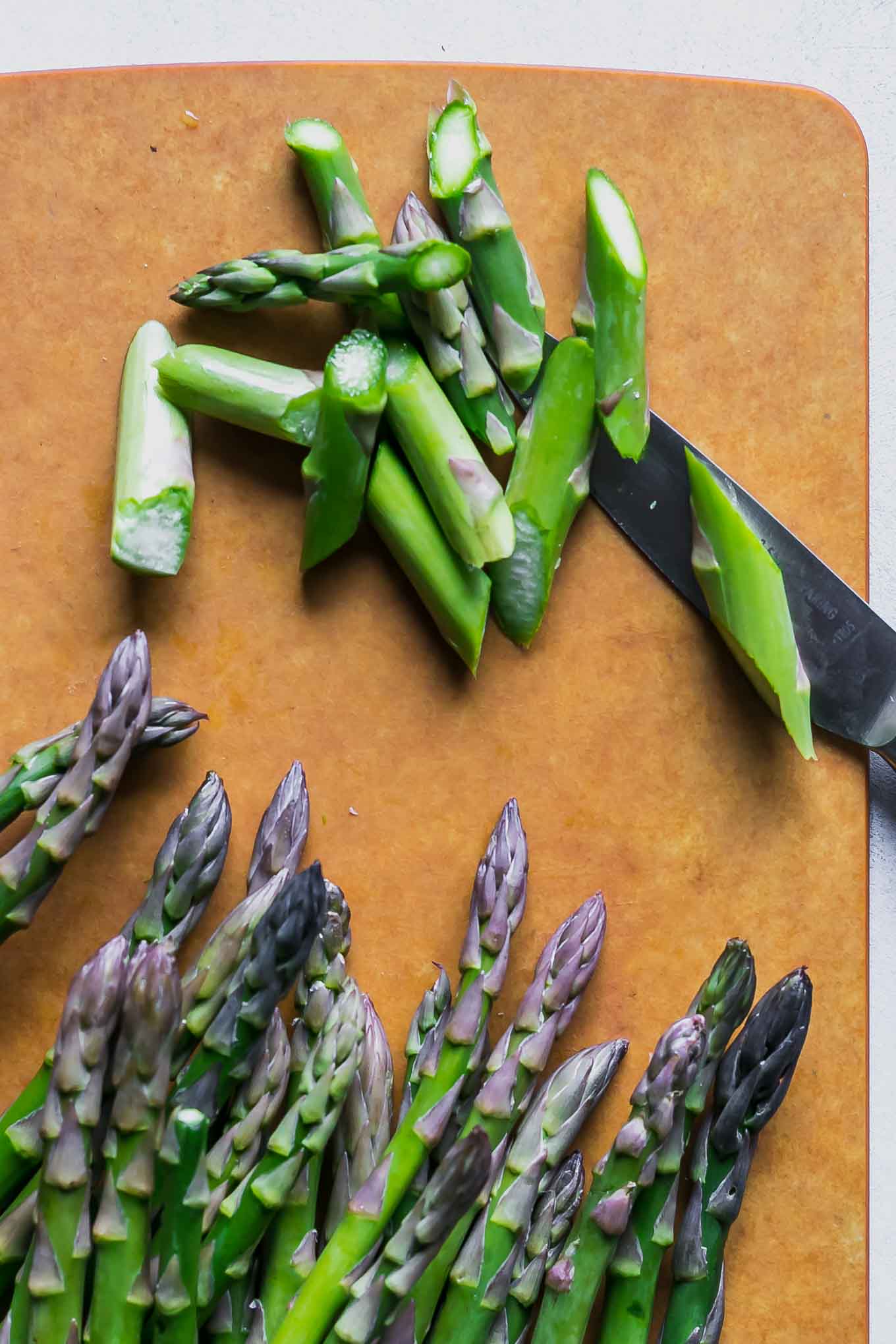 cut asparagus on a wood cutting board with a knife