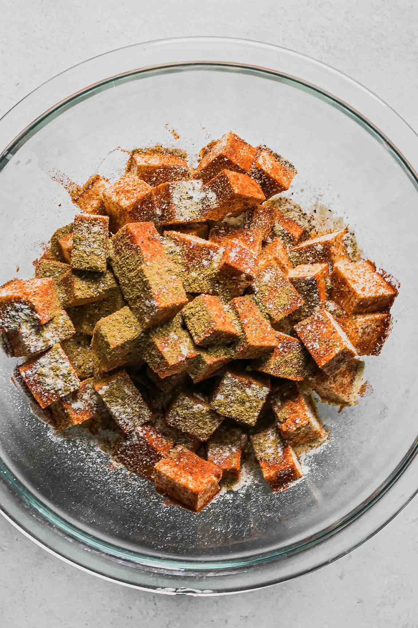 a bowl of cut tofu with fajita seasonings on a white table