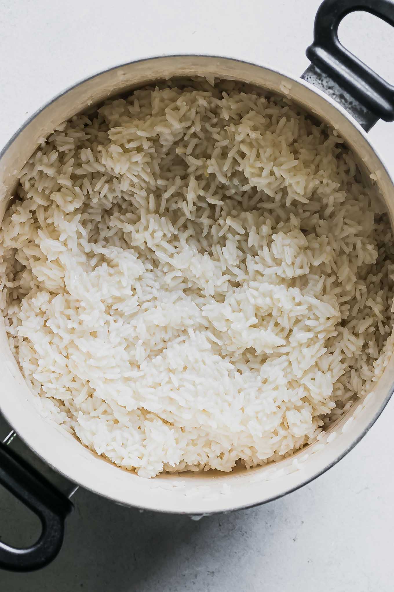 a pot with cooked white rice on a white table
