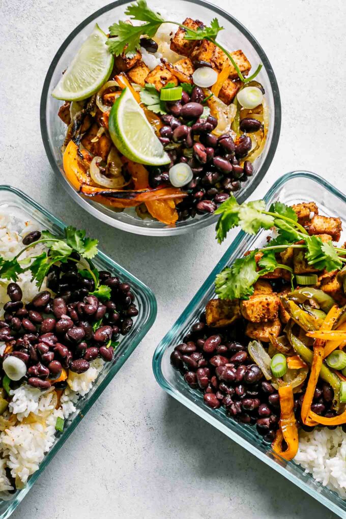 glass food storage bowls with tofu fajitas and rice on a white table for meal prep