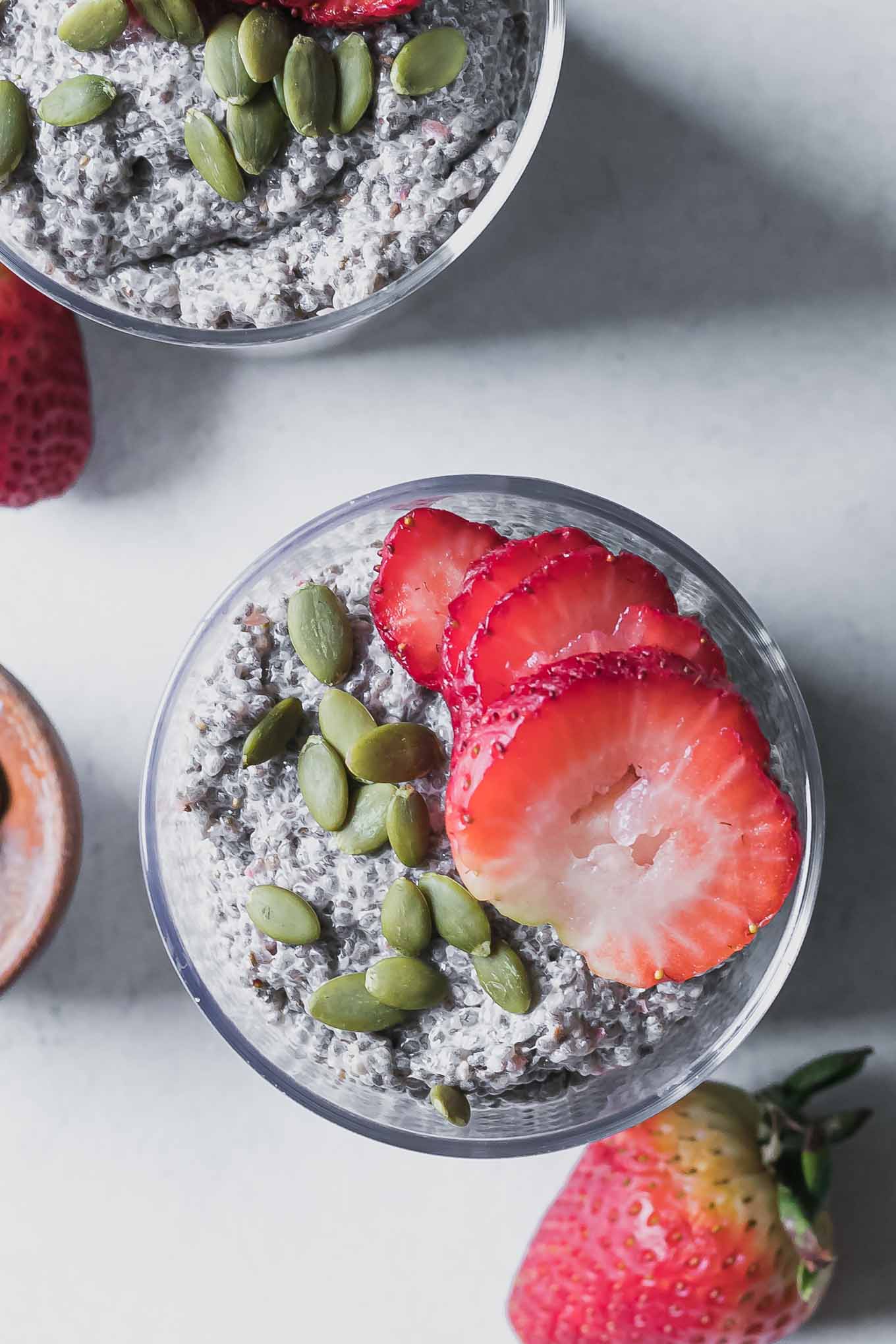 a chia seed pudding topped with sliced strawberries and pumpkin seeds in a glass
