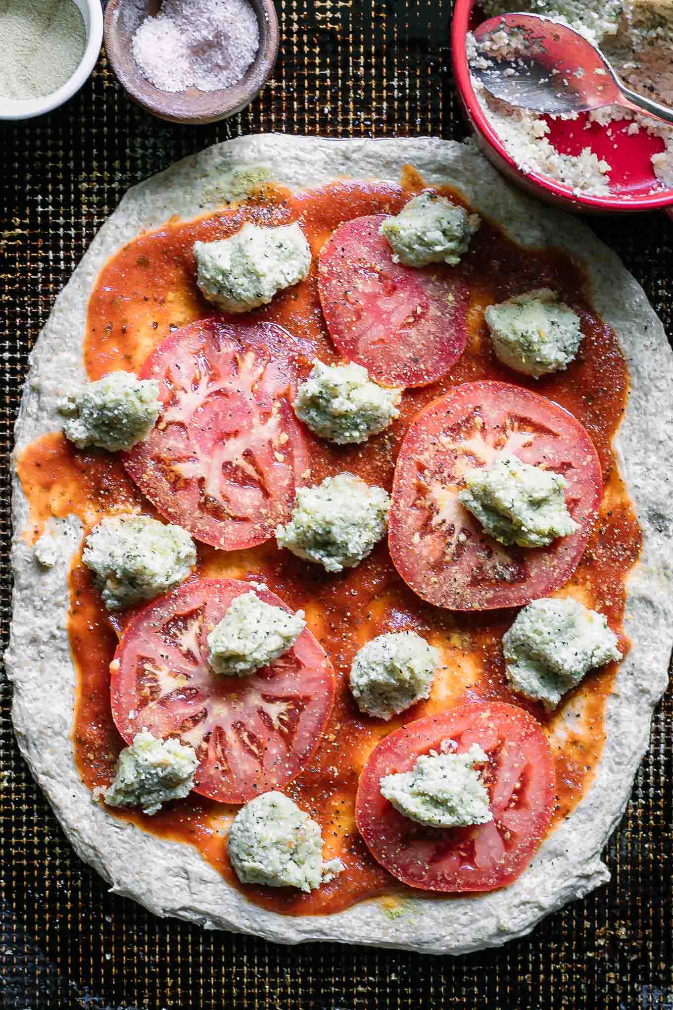 an uncooked plant-based margherita pizza on a baking sheet
