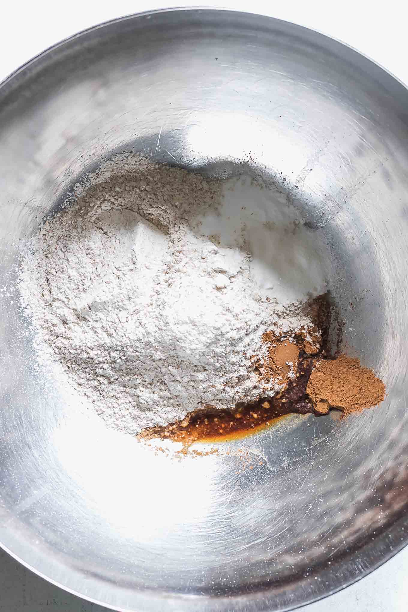 a mixing bowl with whole wheat flour, baking soda, sugar, salt, cinnamon, vanilla extract