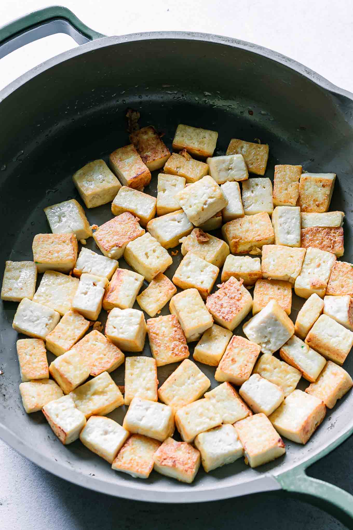 crispy browned and cooked tofu in a pan on a white table