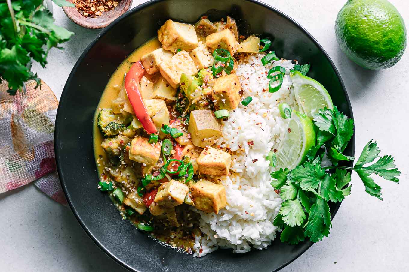 a yellow curry tofu bowl with white rice on a white table