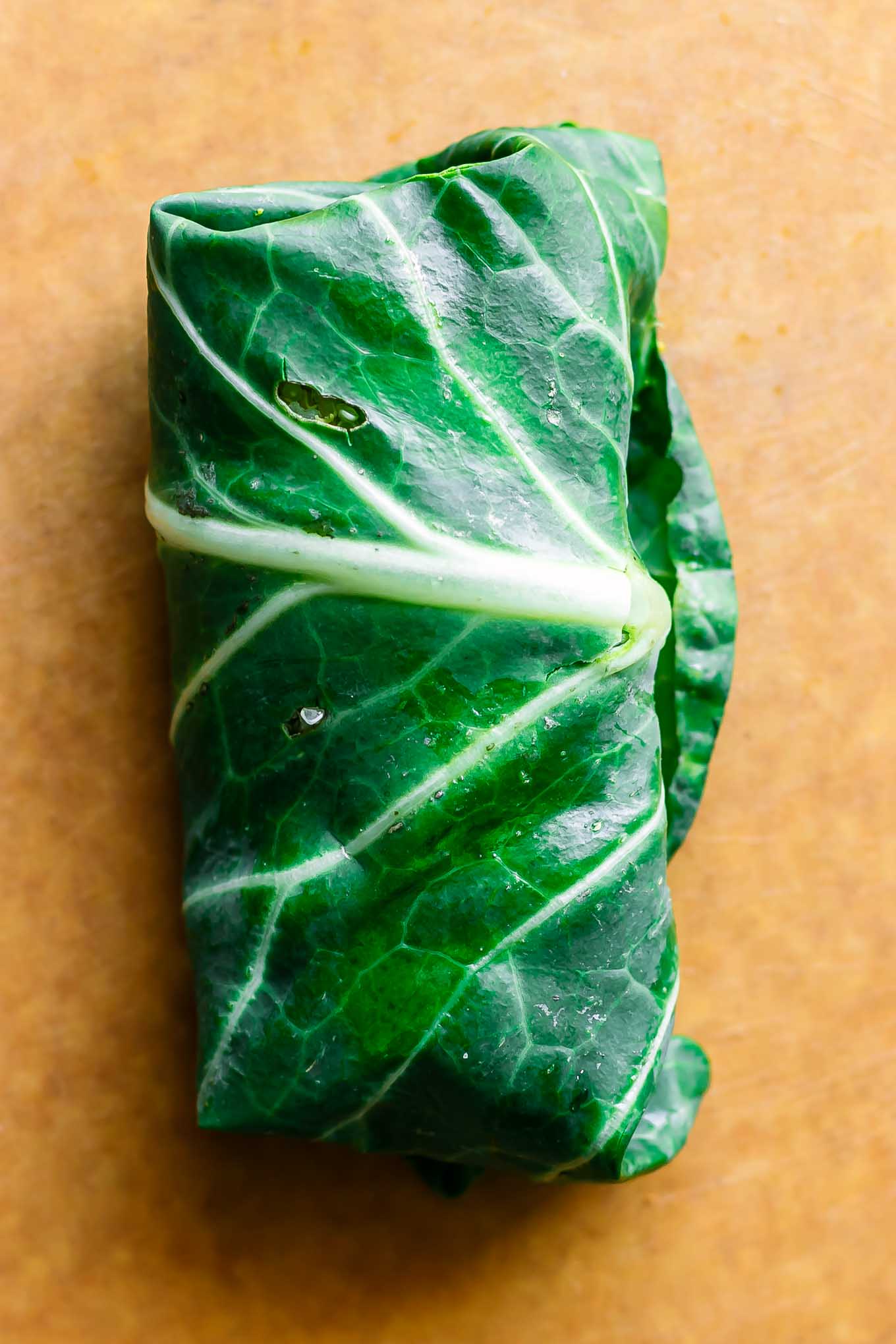 a collard greens wrap on a wood cutting board