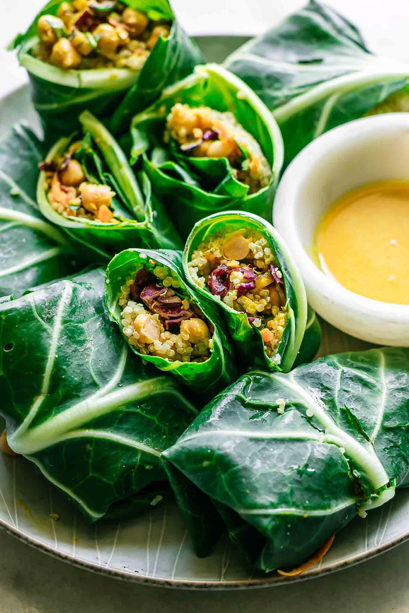 a close up photo of collard greens wraps filled with chickpeas, quinoa, and vegetables on a plate