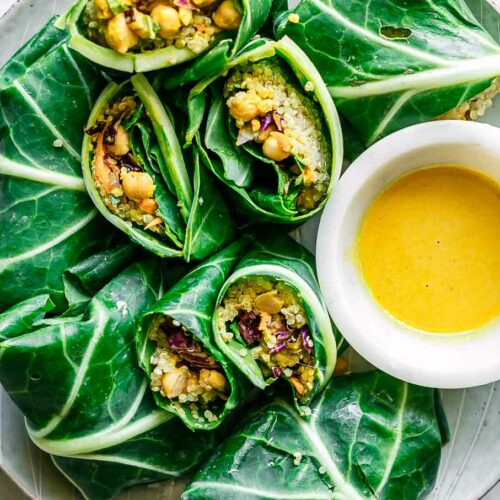 collard greens wraps with chickpea quinoa tahini curry salad on a white plate on a white table