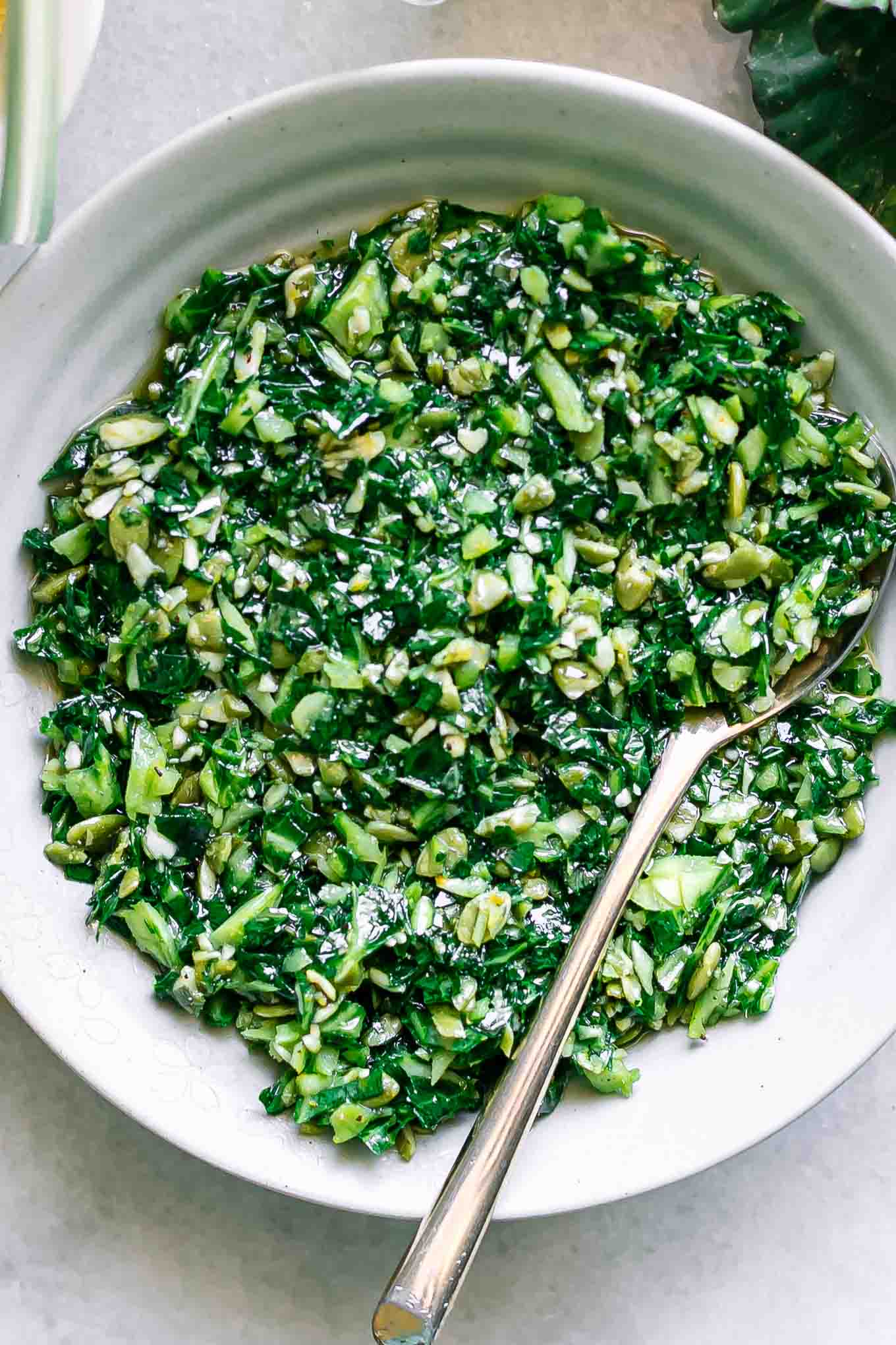 a close up of pesto with collard greens in a white bowl