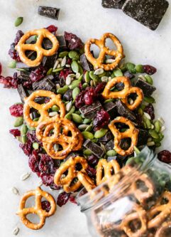 trail mix with pretzels, dark chocolate, dried cranberries, and pumpkin and sunflower seeds on a white table