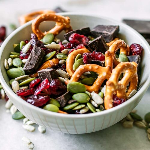 a small bowl with dark chocolate and dried cranberry trail mix with pretzels and seeds