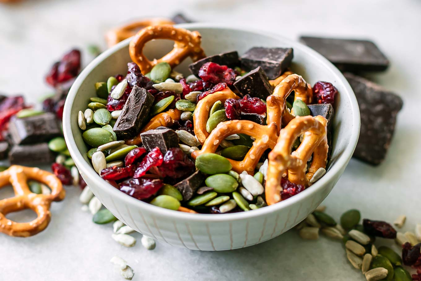 a small bowl with dark chocolate and dried cranberry trail mix with pretzels and seeds