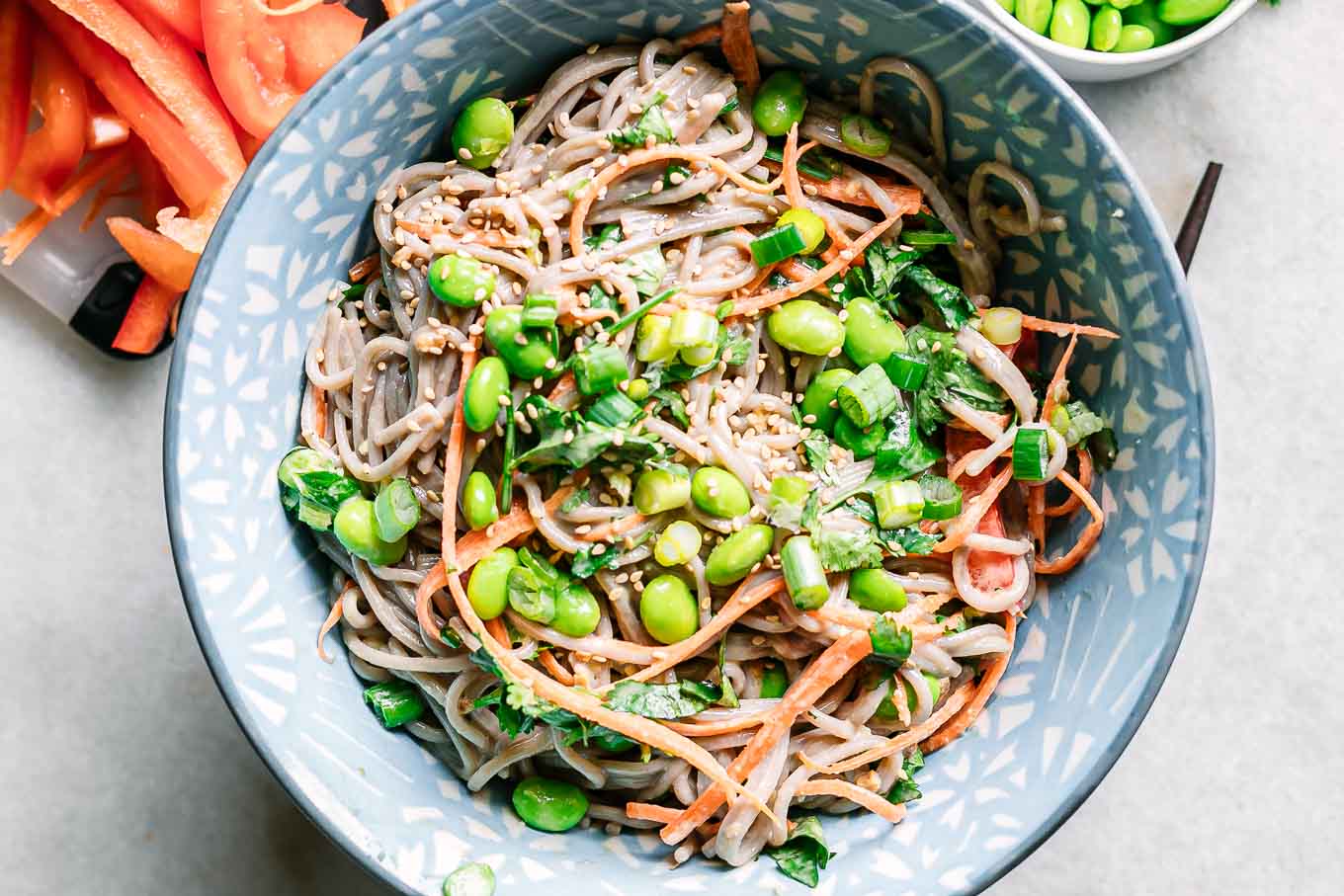 a blue bowl with sesame ginger soba noodle salad on a white table