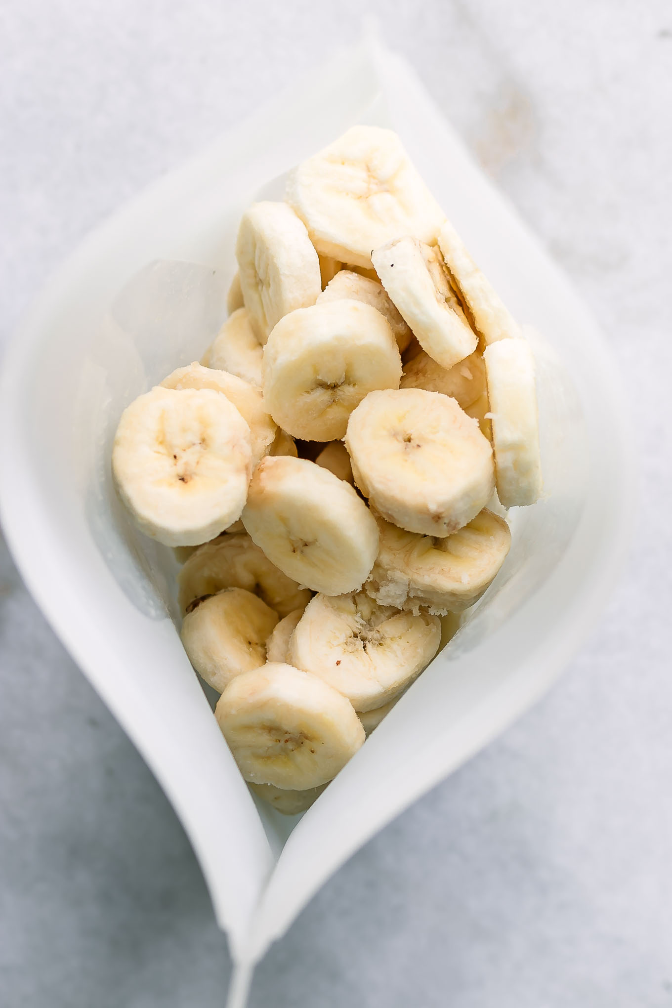 a silicone freezer bag with frozen sliced bananas on a white table