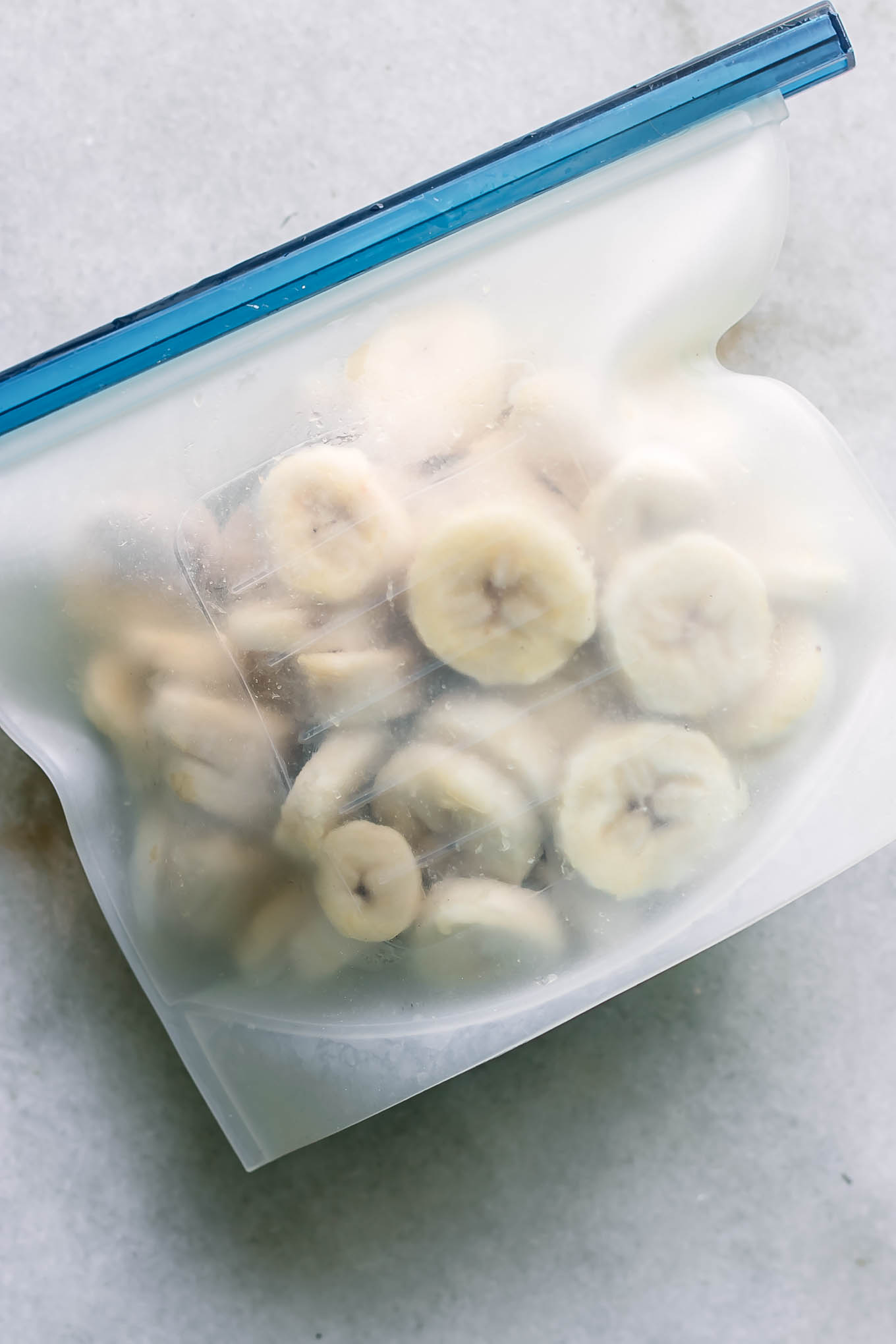 frozen banana slices in a silicone freezer bag on a white table