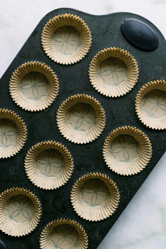 a muffin pan with muffin liners on a white table