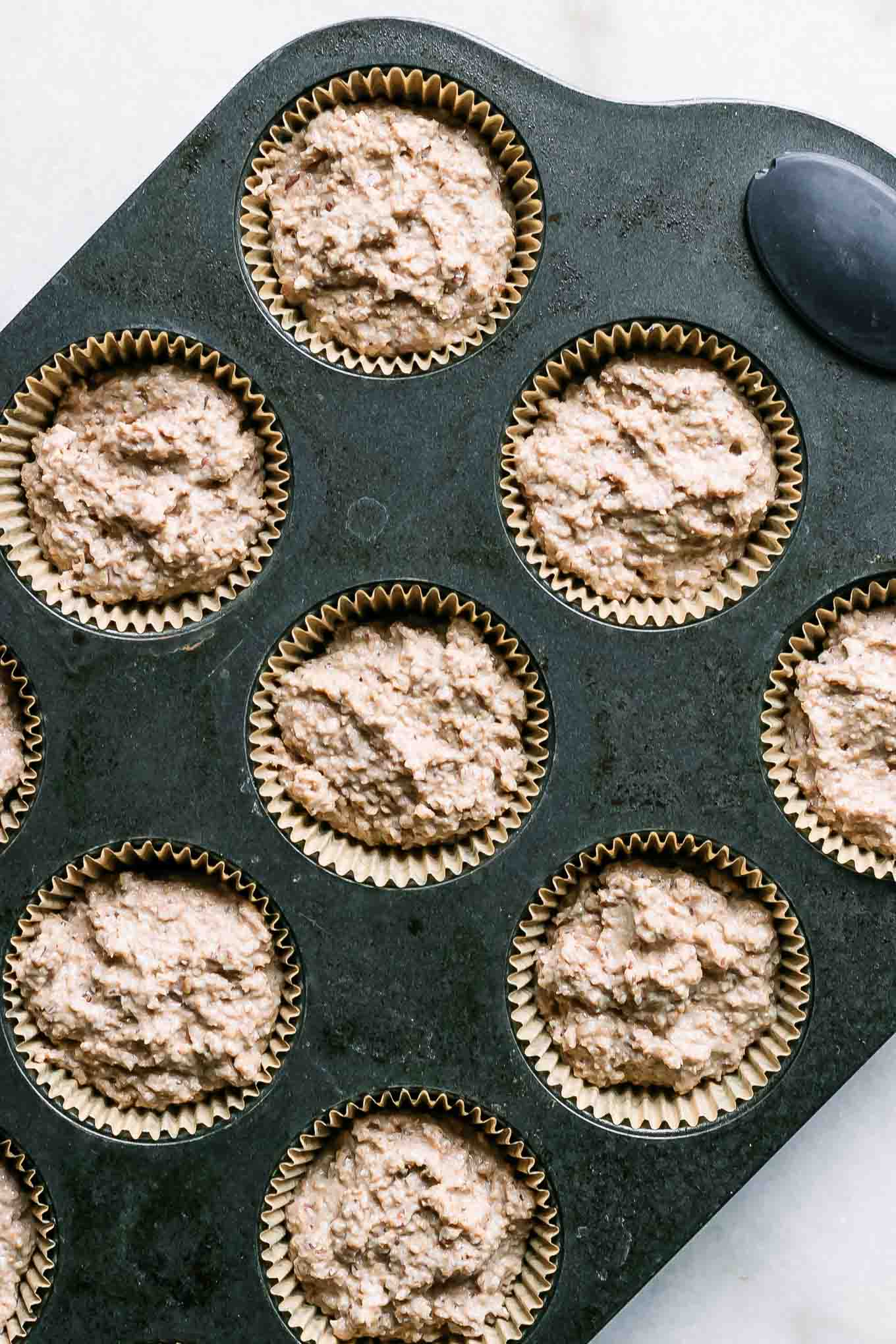 muffin batter inside muffin tins on a white table before baking