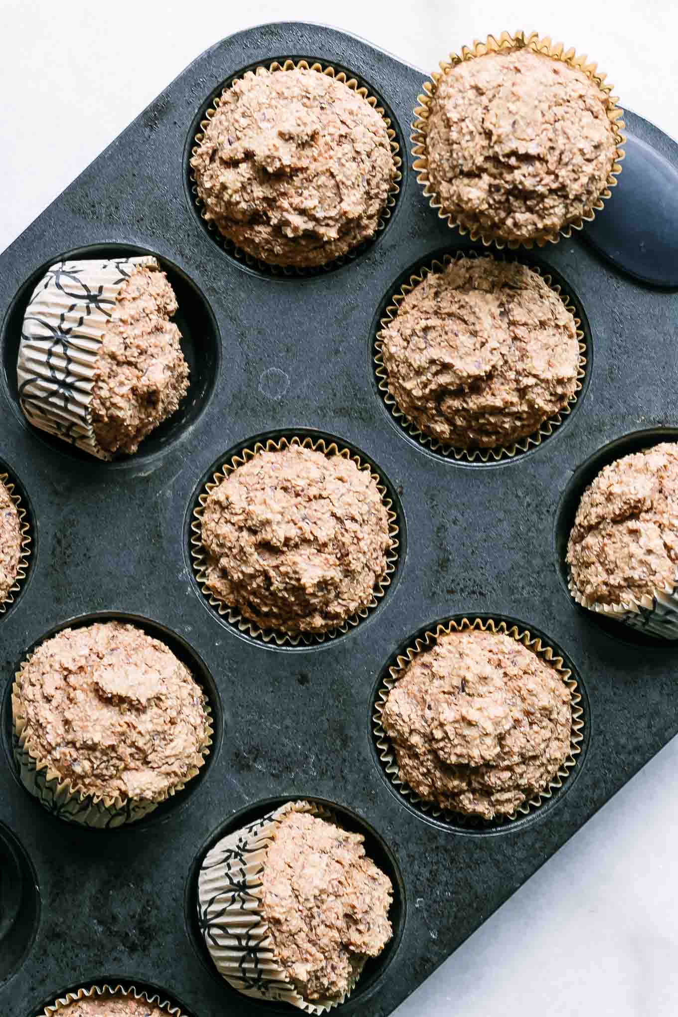 a muffin pan with cooked vegan bran muffins on a white table
