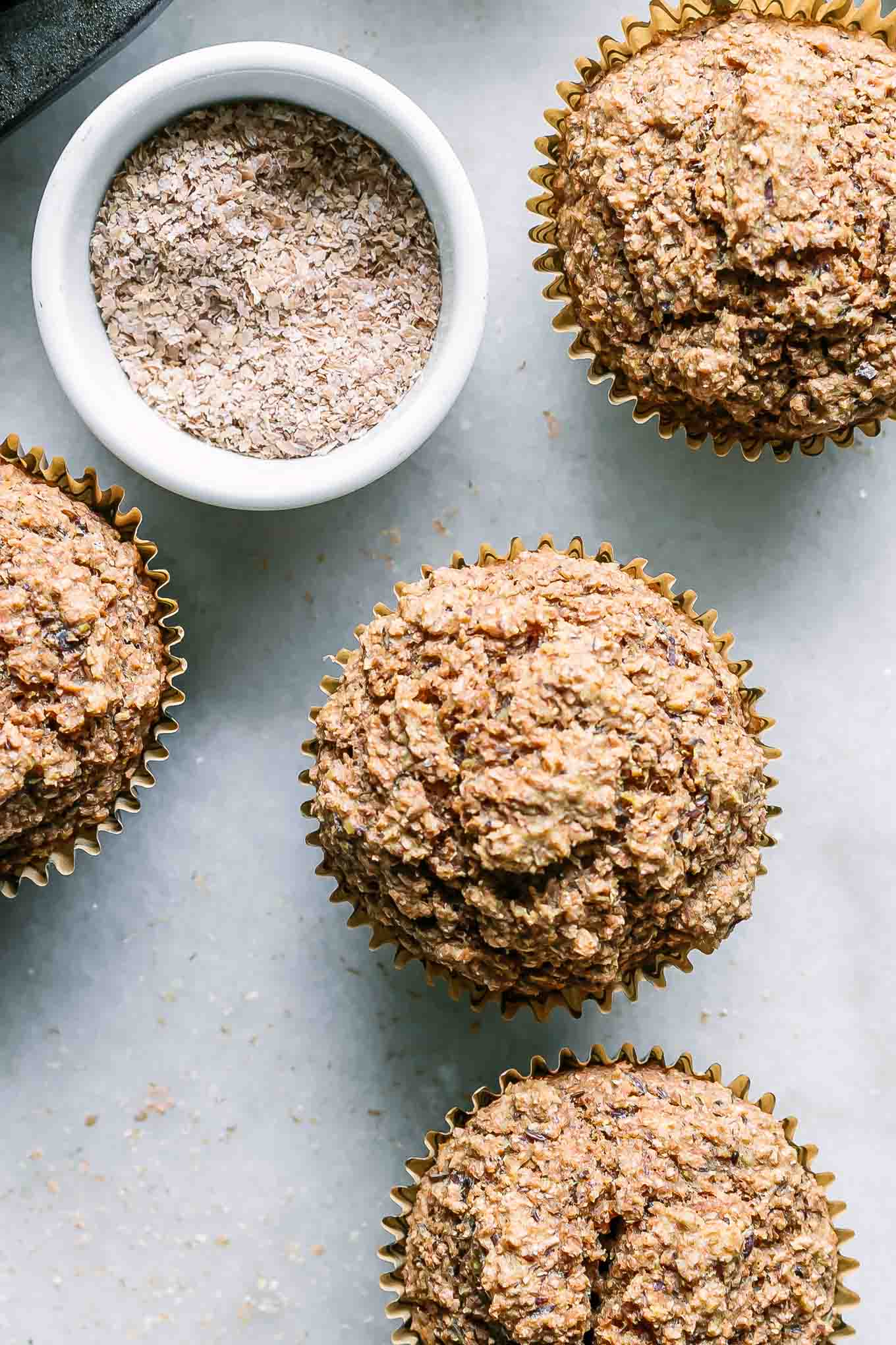 a close up photo of the top of bran muffins on a white table