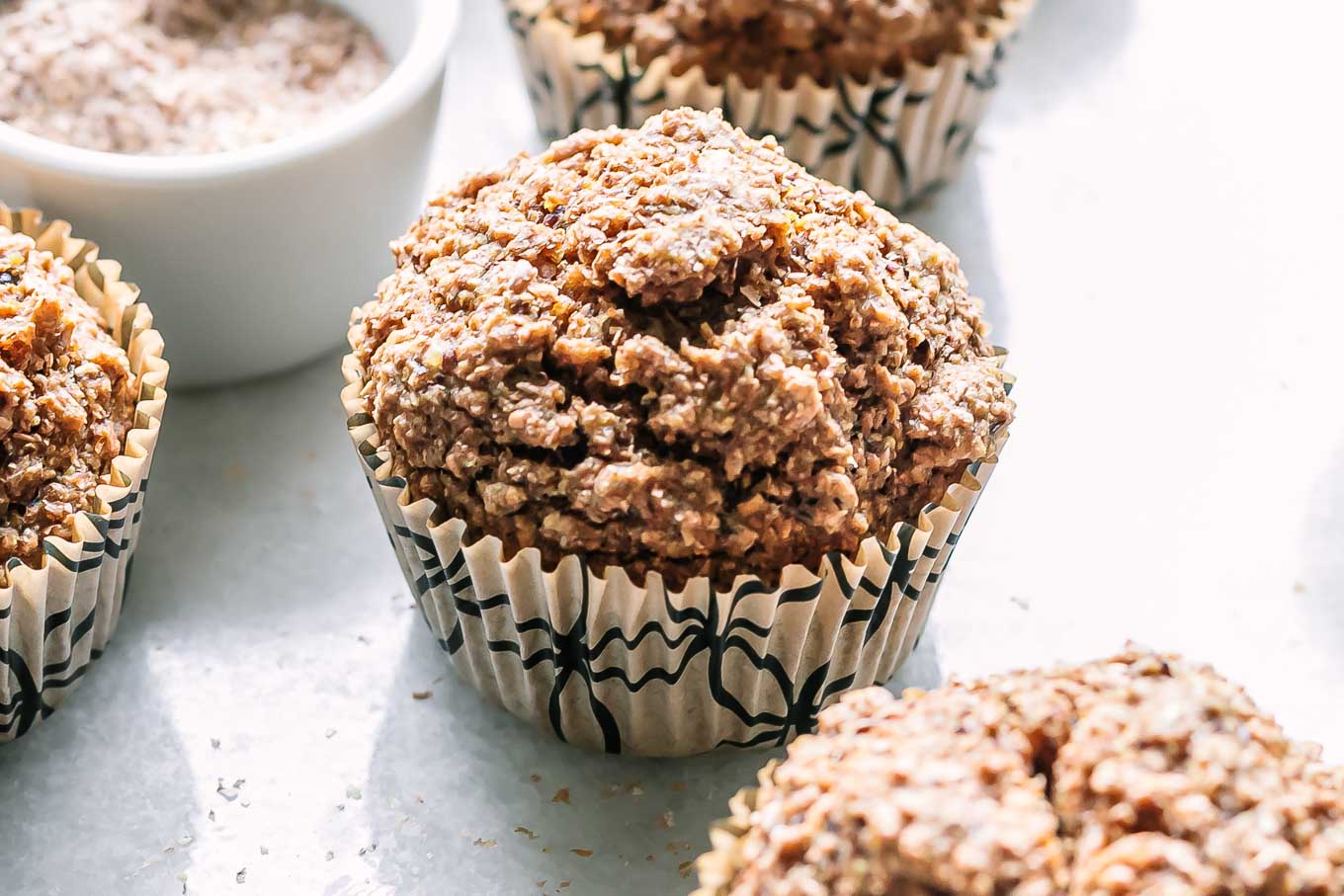 bran muffins in recycled paper muffin liners on a white table