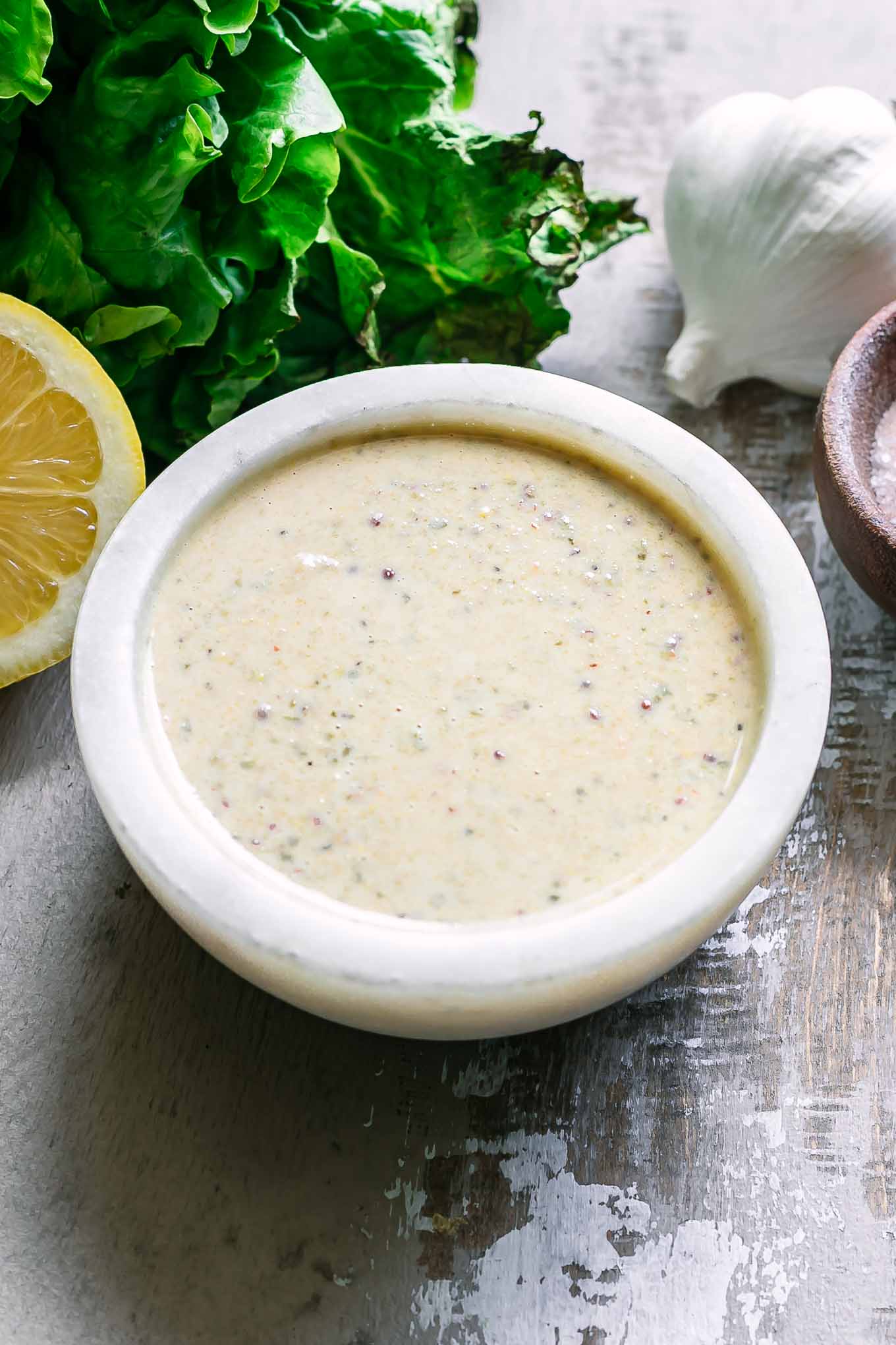 a bowl of vegan caesar dressing in a white bowl on a wood table