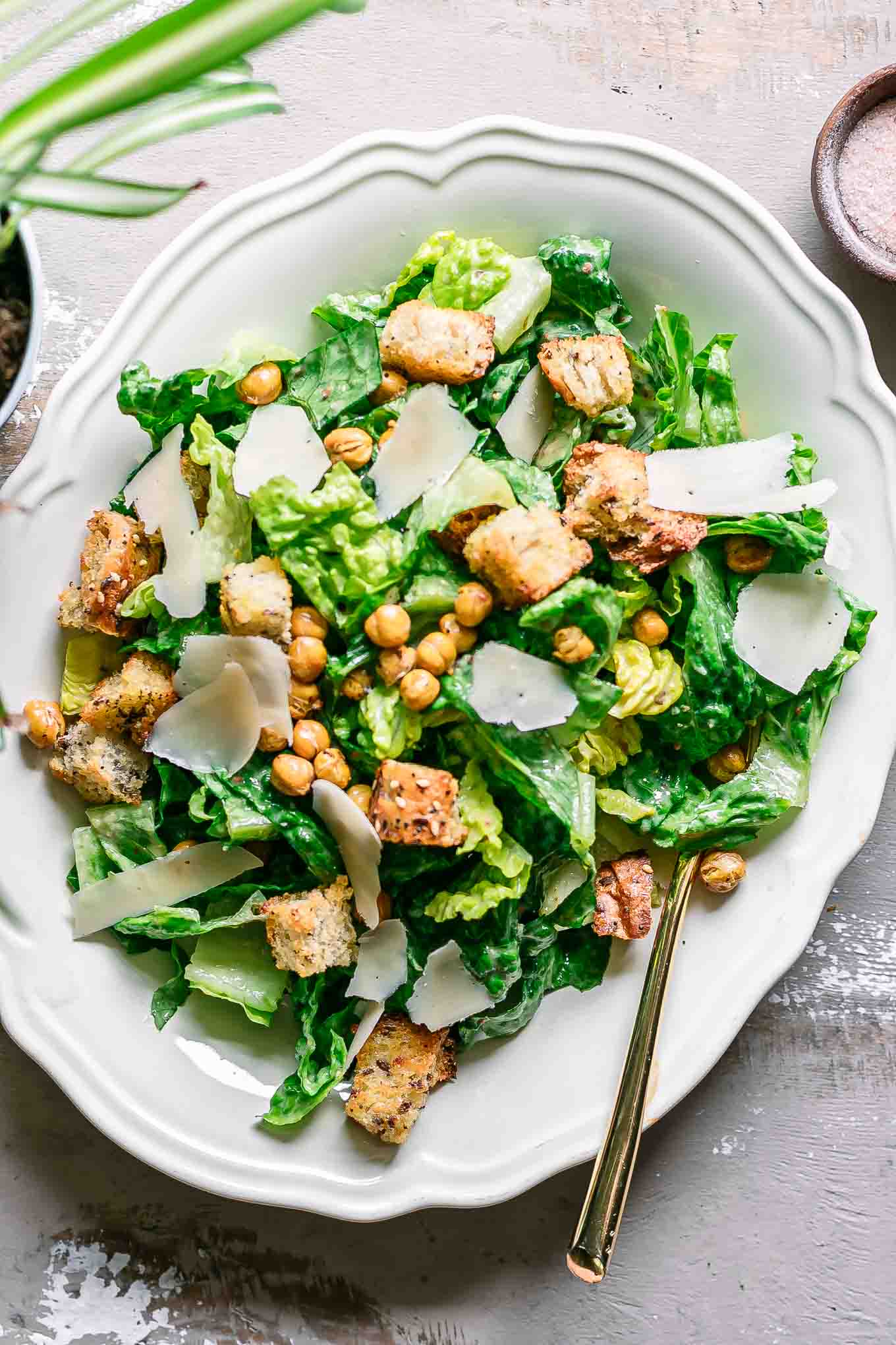 a vegan caesar salad on a white plate on a wood table