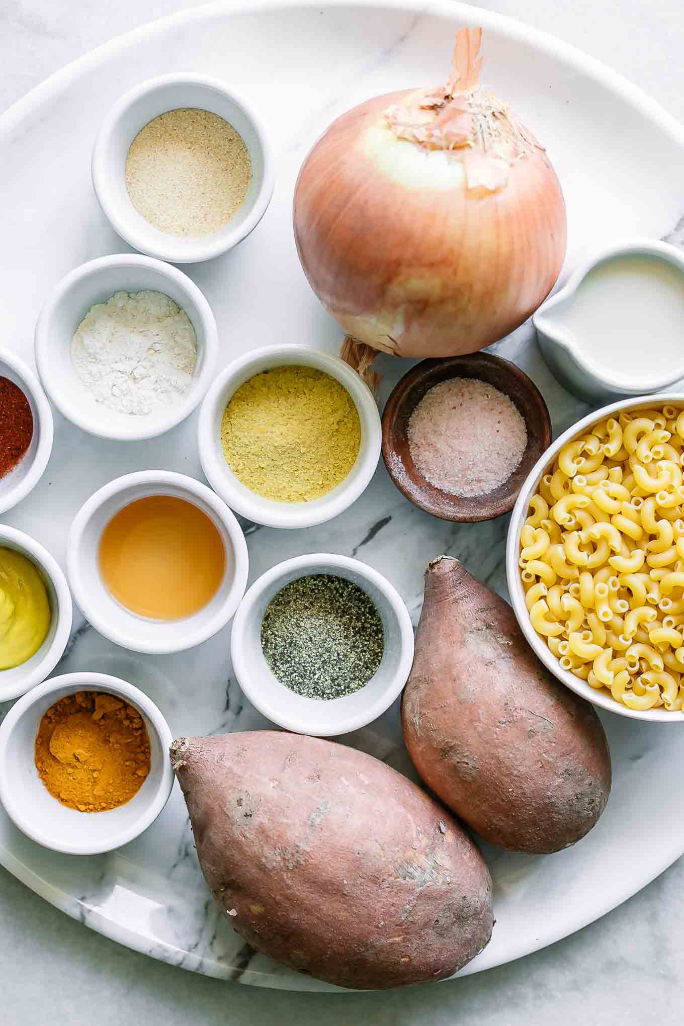 sweet potatoes, onion, garlic, macaroni, and spices on a table for swet potato macaroni