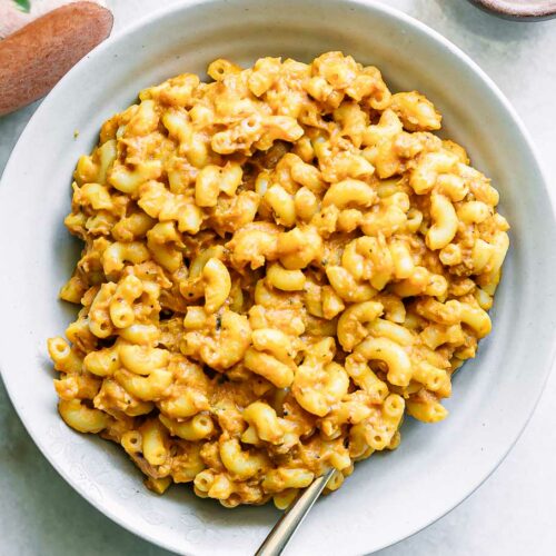 a white plate with sweet potato macaroni and cheese with a gold fork