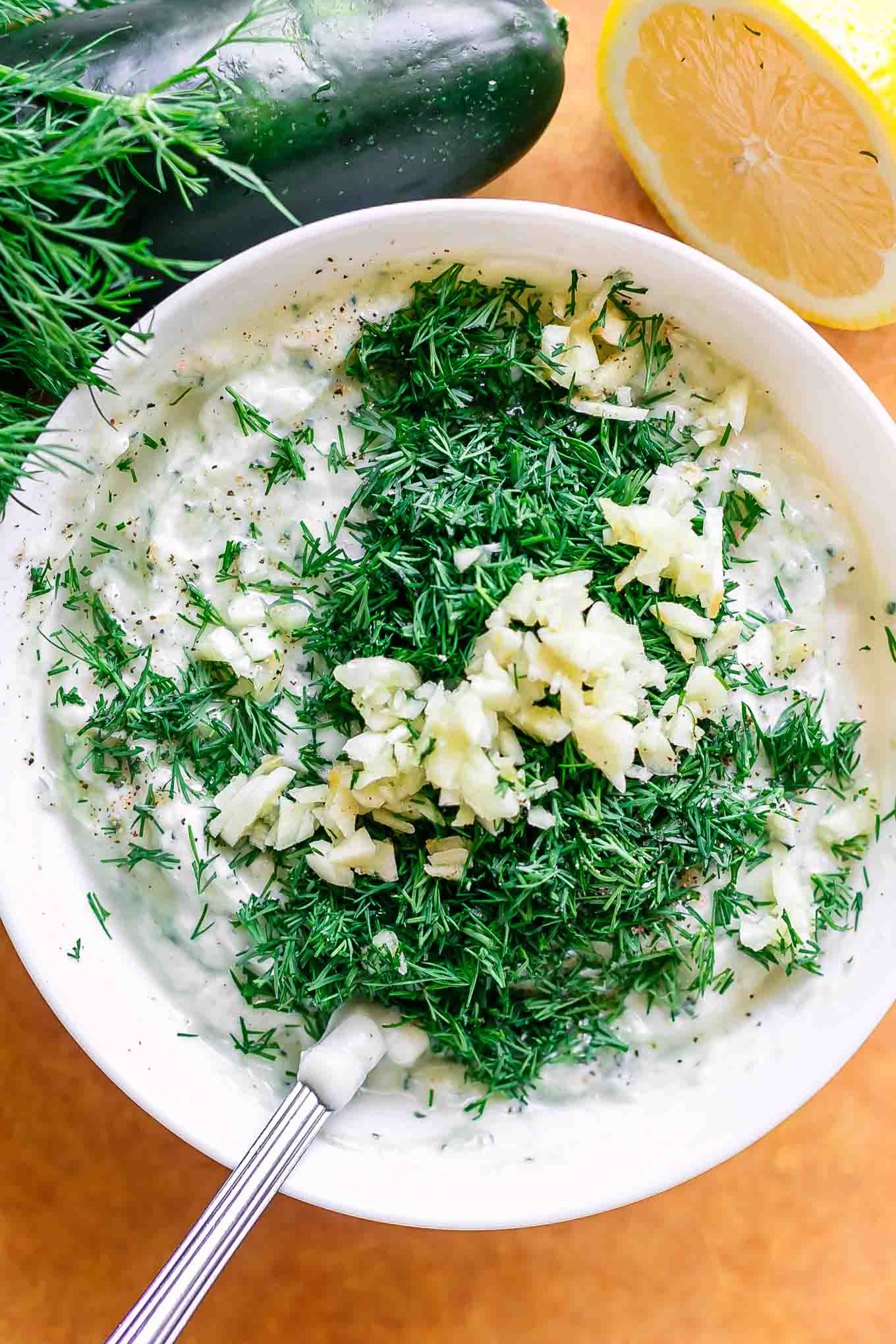 a bowl with yogurt, dill, garlic, and lemon for tzatziki sauce