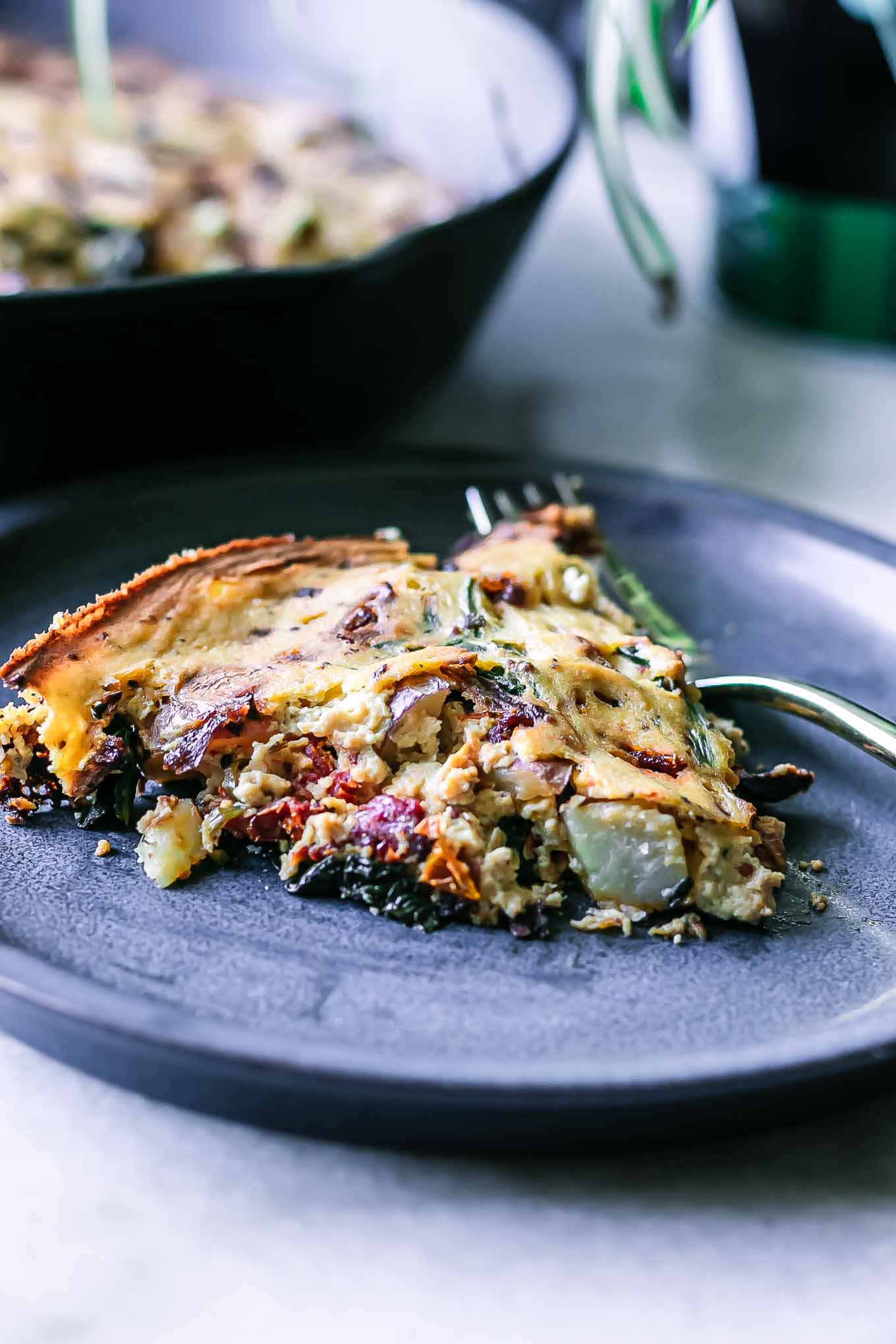 a side view of a slice of vegan tofu frittata on a blue plate