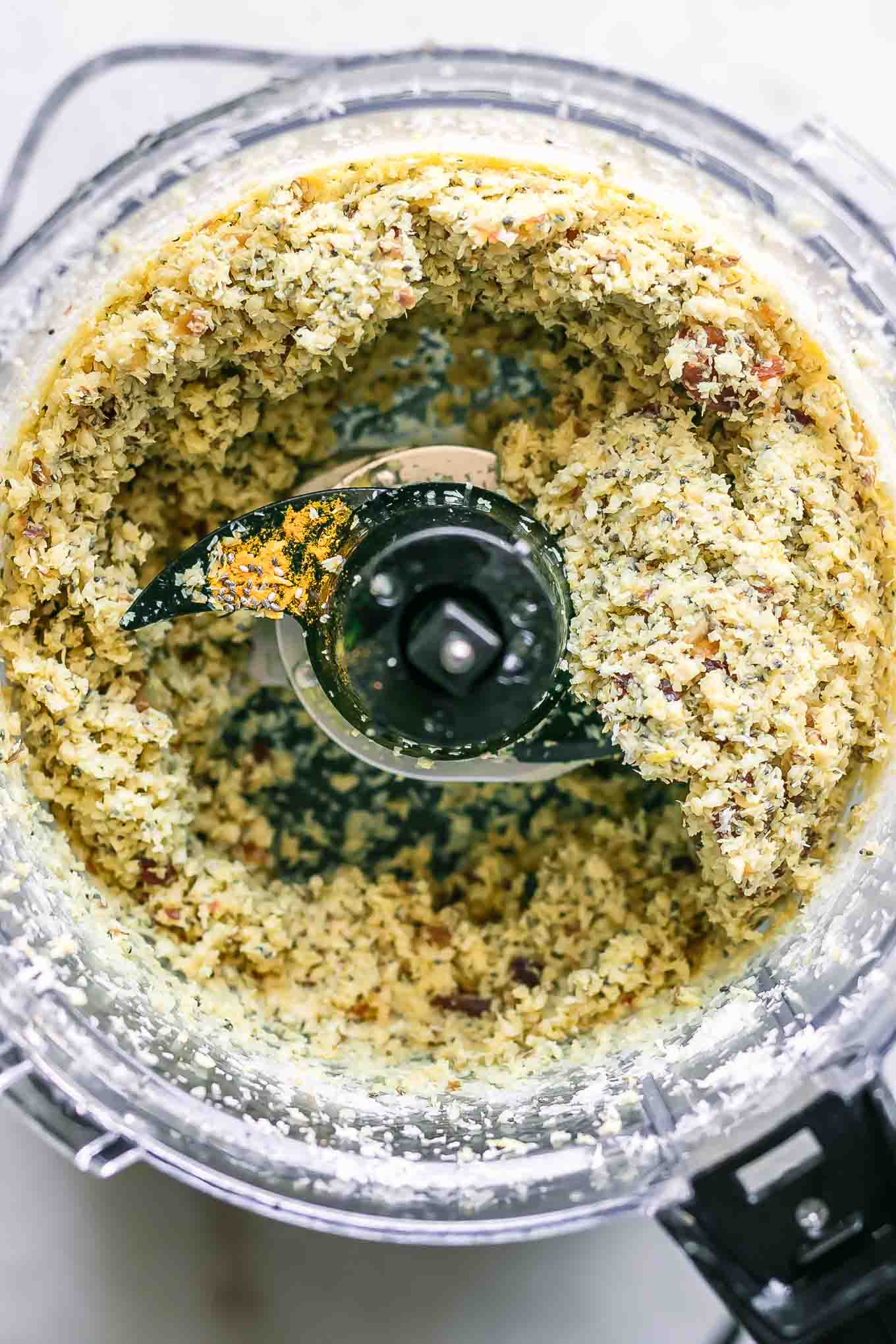 a food processor with blended cashews, coconut, and lemon zest for energy balls