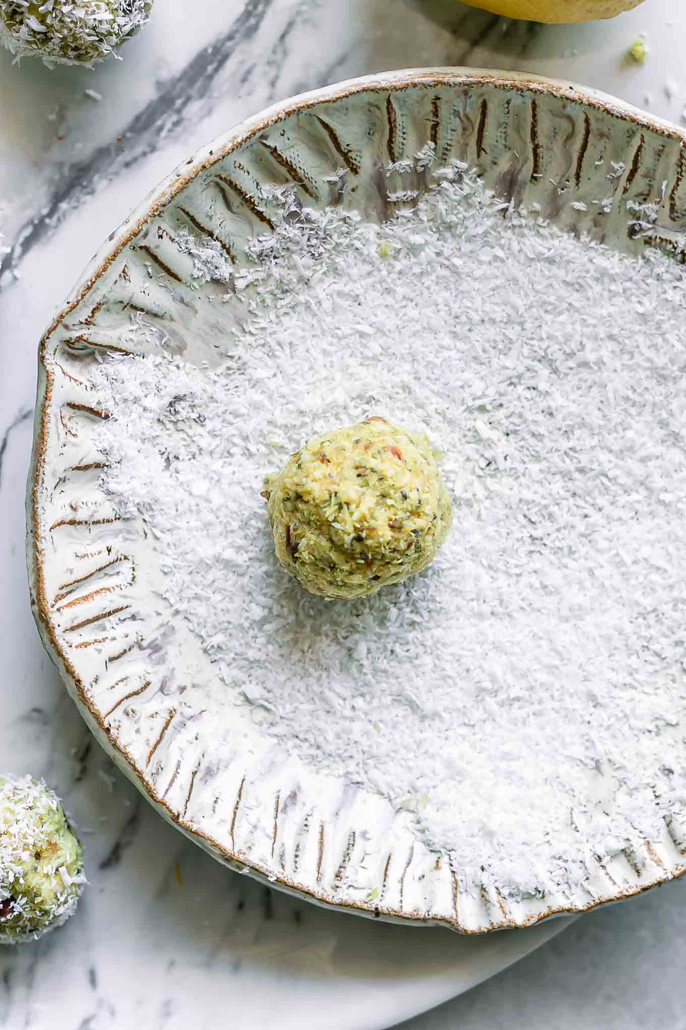 a plate with coconut flakes and a lemon cashew ball on top