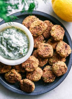baked falafel balls on a blue plate with a white dip on a white table