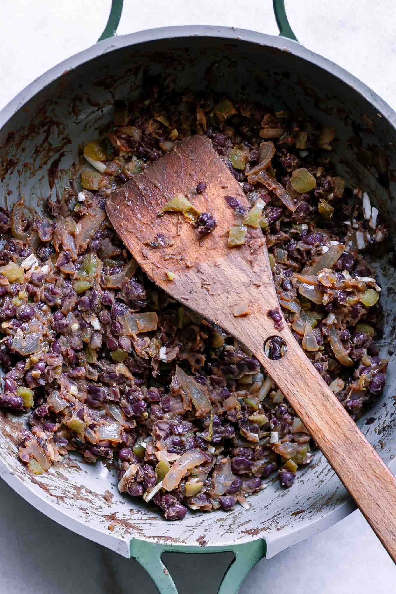 cooked black bean taco filling inside a pan with a wooden spoon