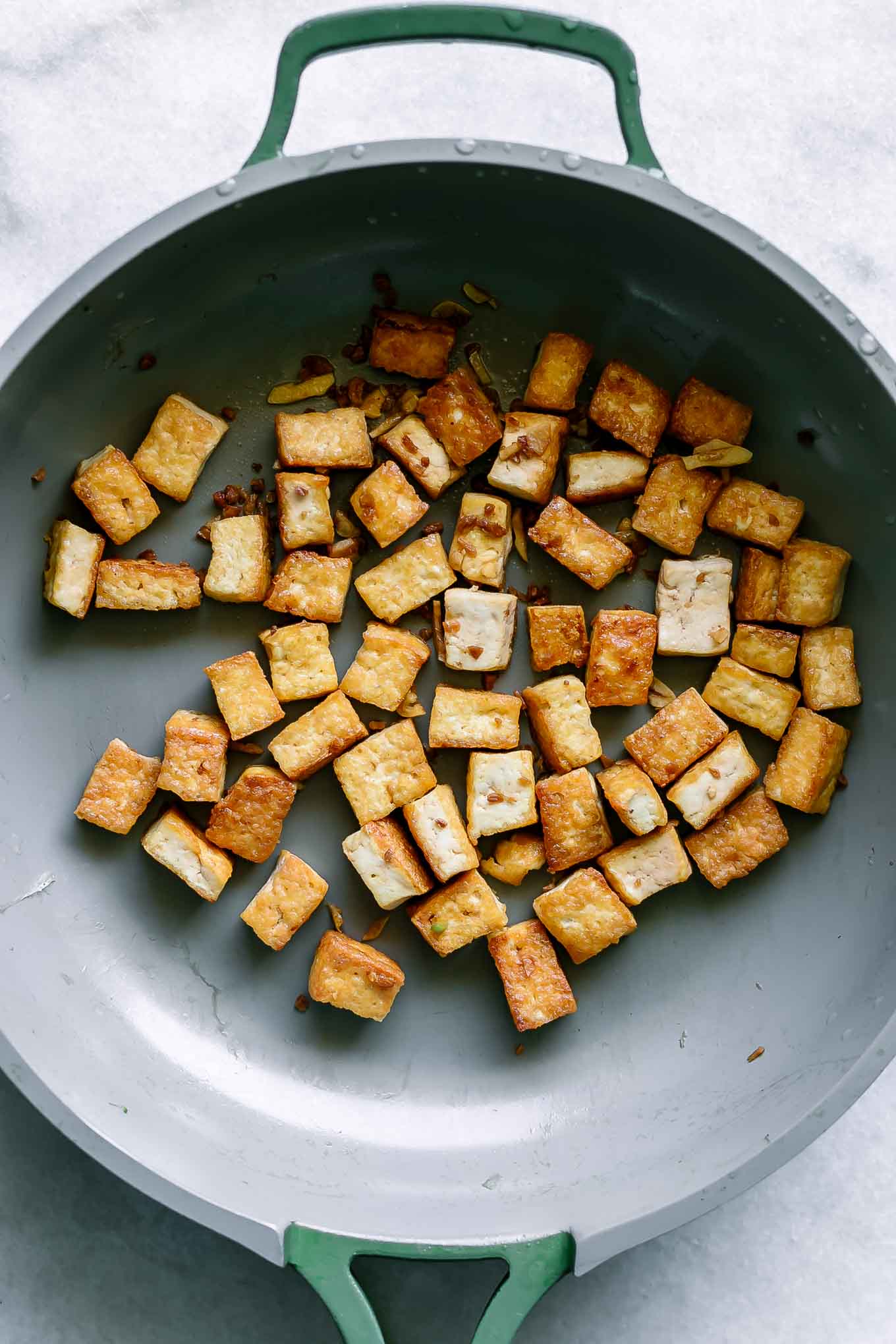 cooked crispy tofu in a pan on a white table