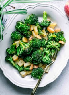 roasted broccoli and apples on a white plate with a gold fork