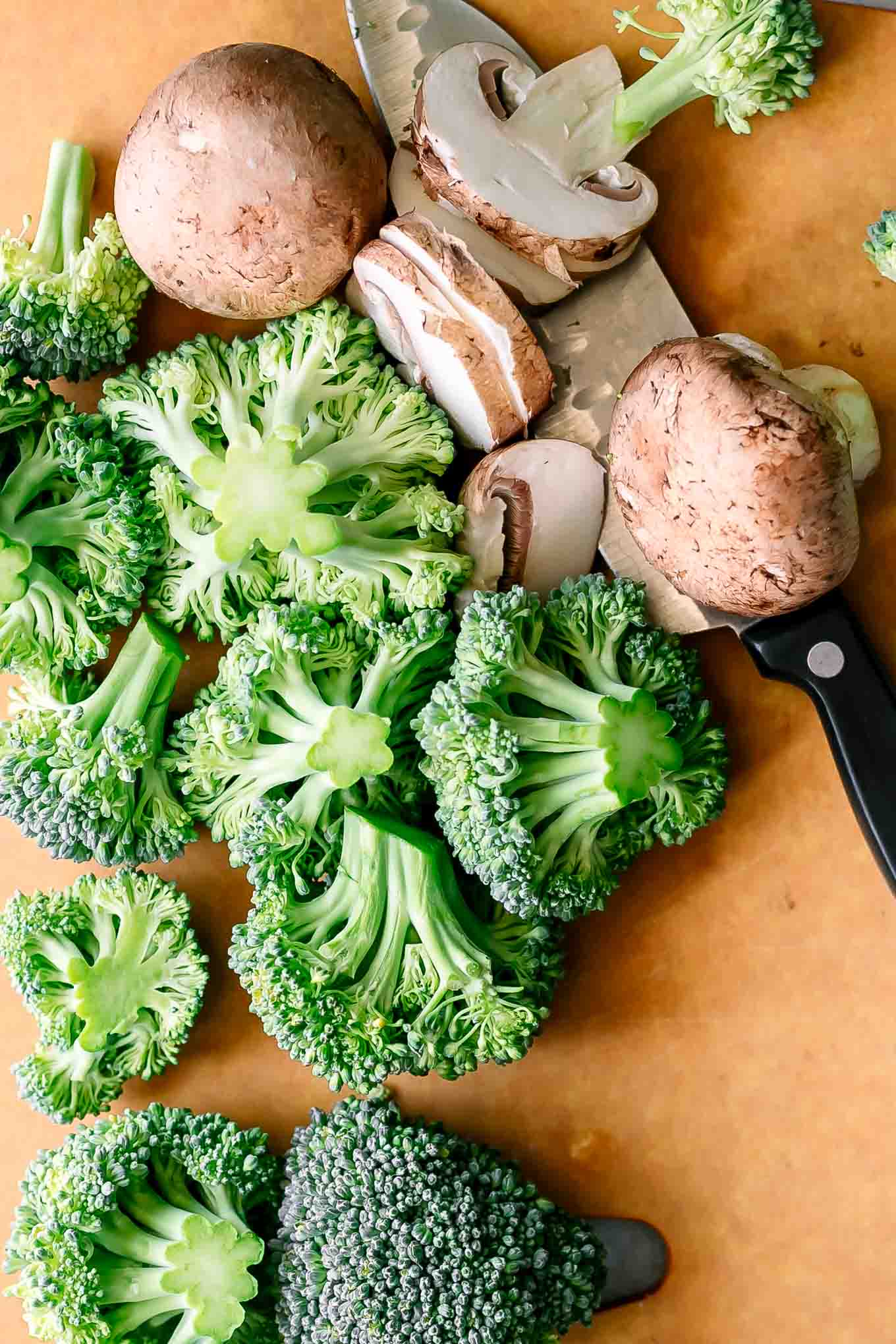 cut broccoli and mushrooms on a cutting board
