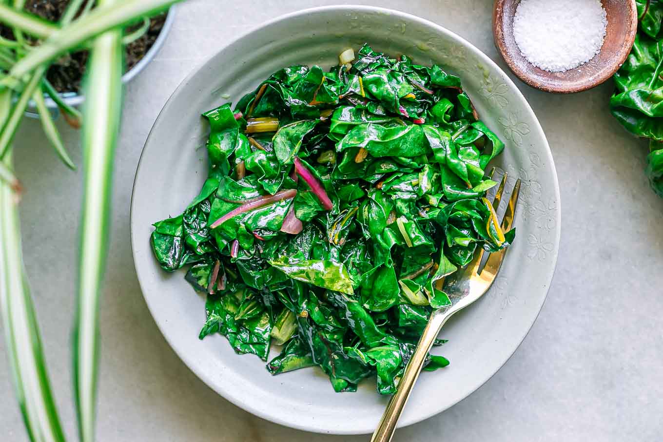 sauteed swiss chard leaves on a plate with a gold fork