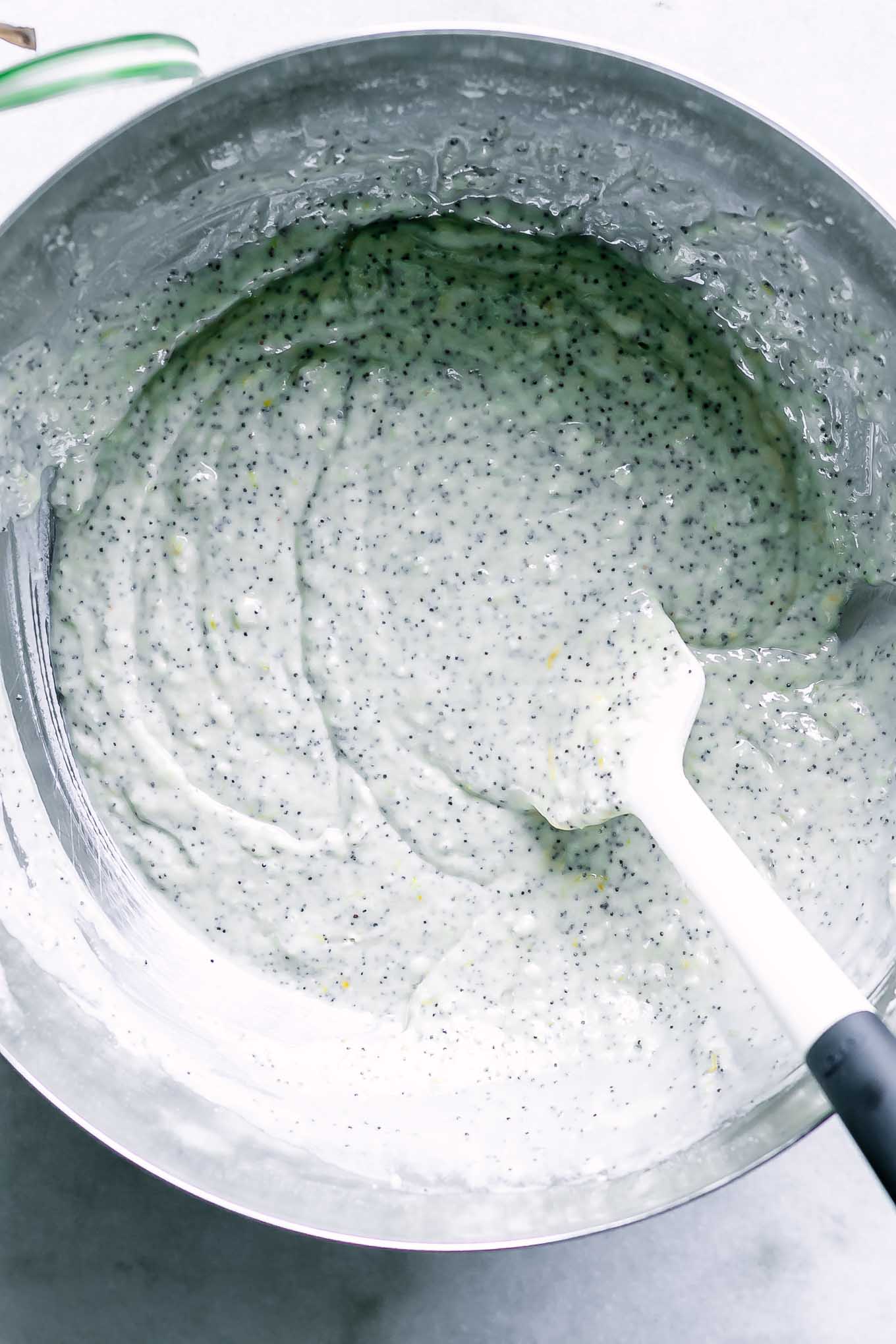lemon poppyseed muffin batter inside a mixing bowl with a baking spatula