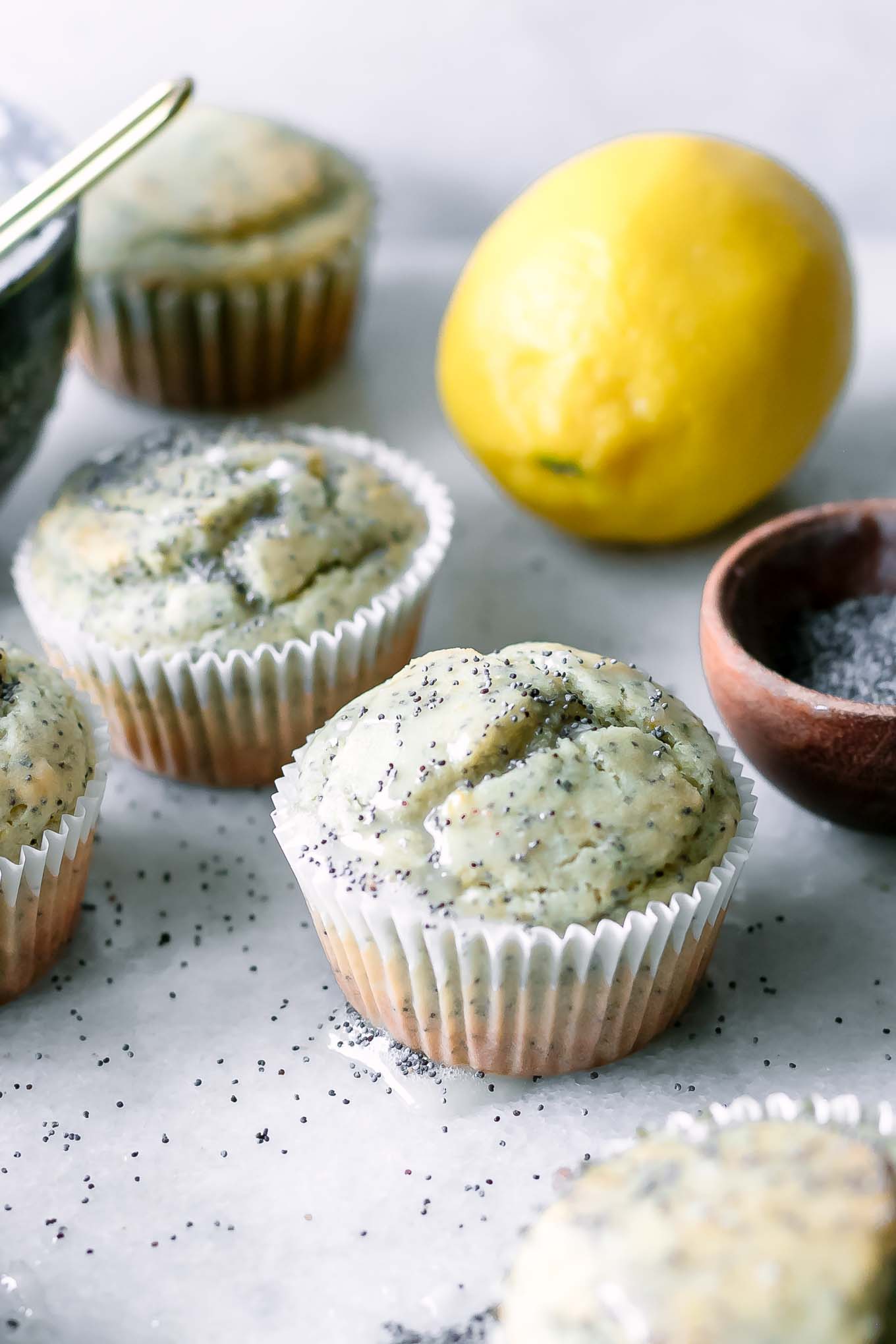 plant-based lemon poppyseed muffins on a white table with a lemon