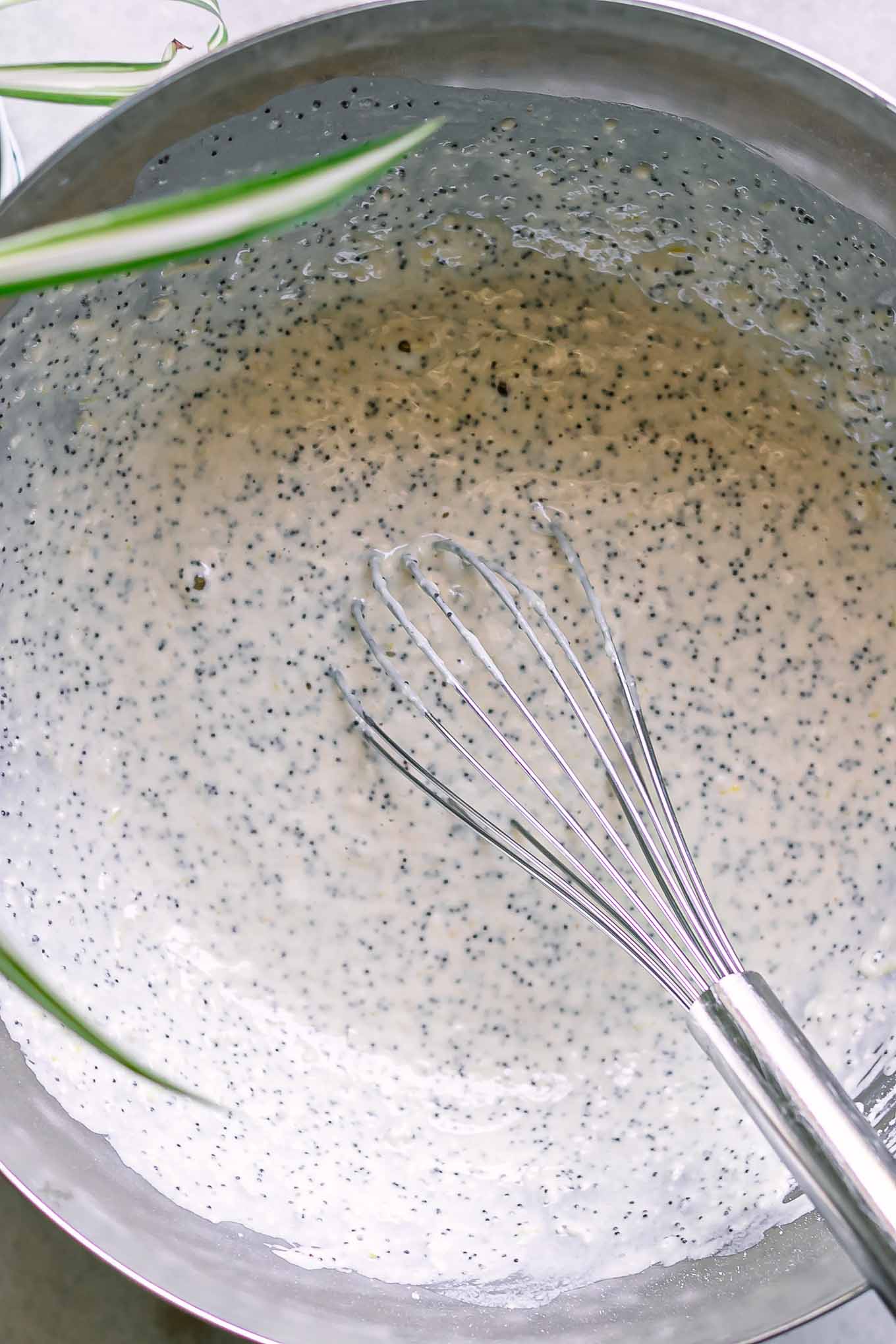 a mixing bowl with lemon poppyseed pancake batter inside with a metal whisk