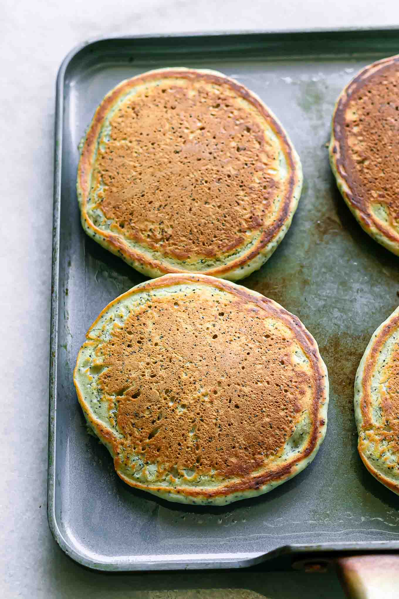 poppyseed pancakes cooking on a flat blue pan