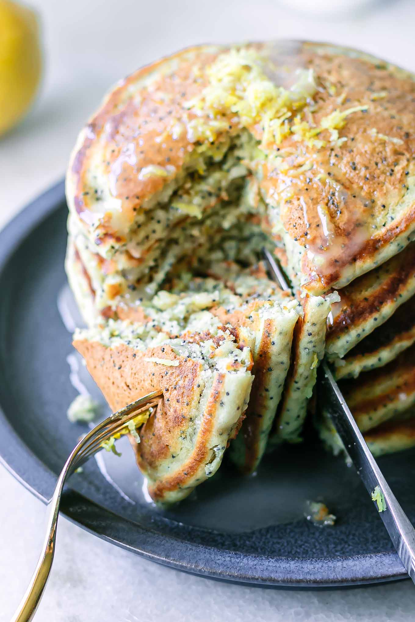 a stack of lemon poppyseed pancakes with a fork cutting pancake pieces