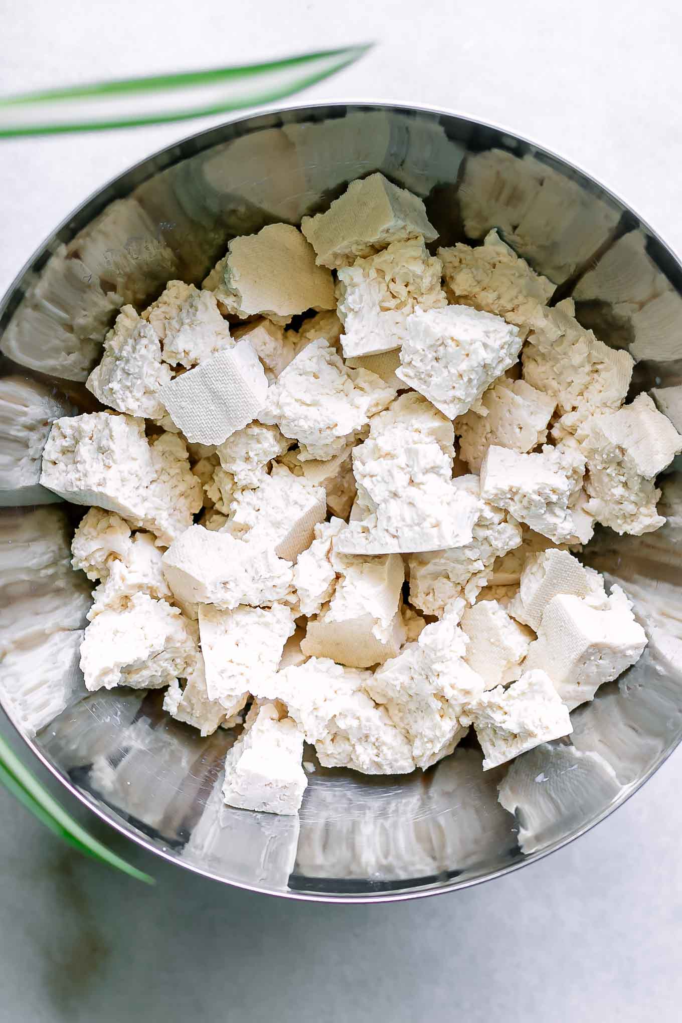 a metal bowl with torn tofu