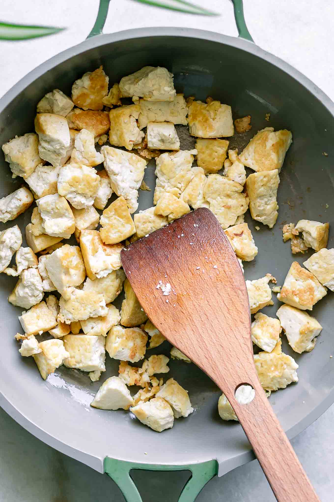 cooked and browned tofu inside a pan with a wood spatula