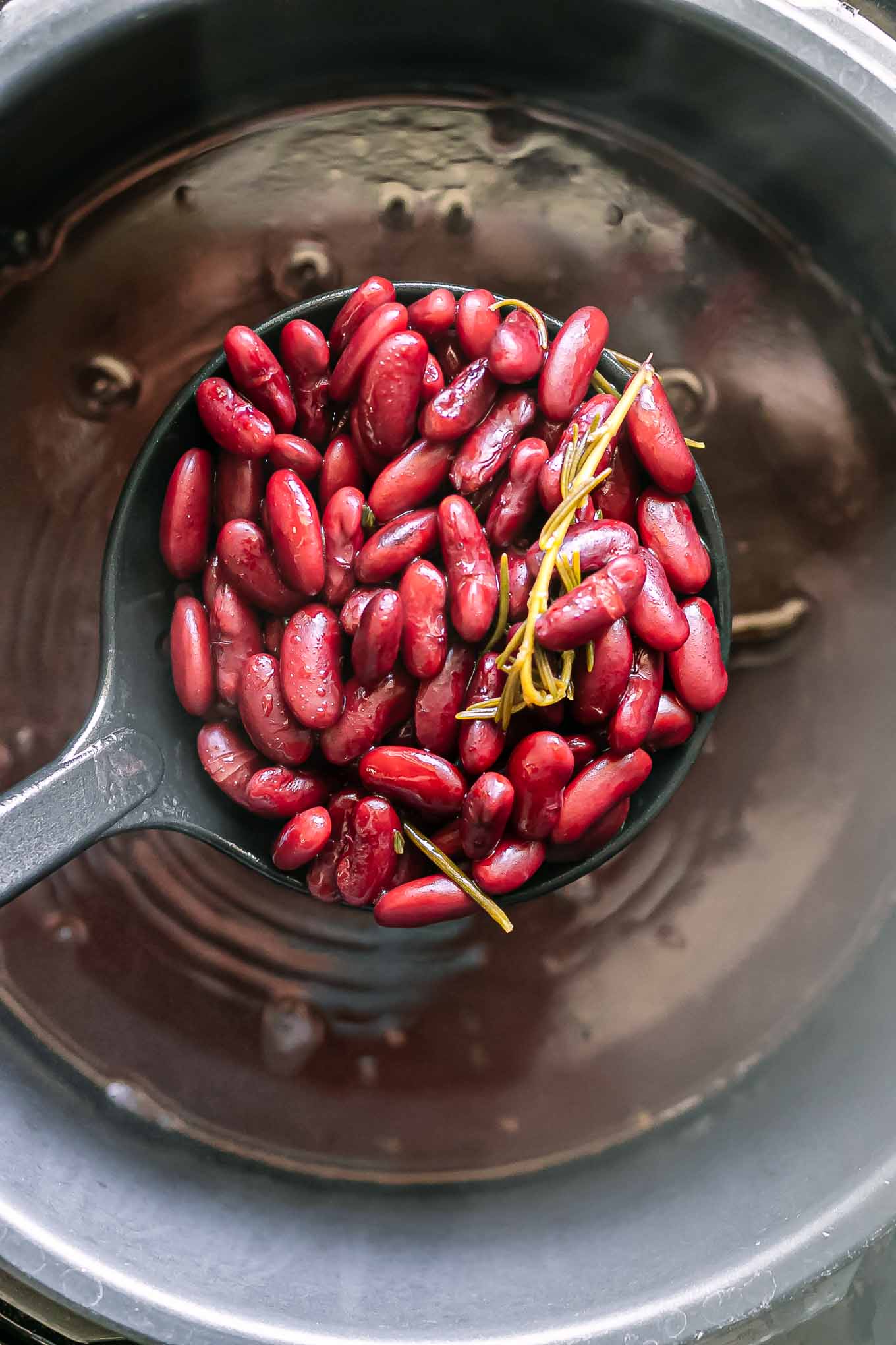 a spoon lifting cooked kidney beans out of a pressure cooker