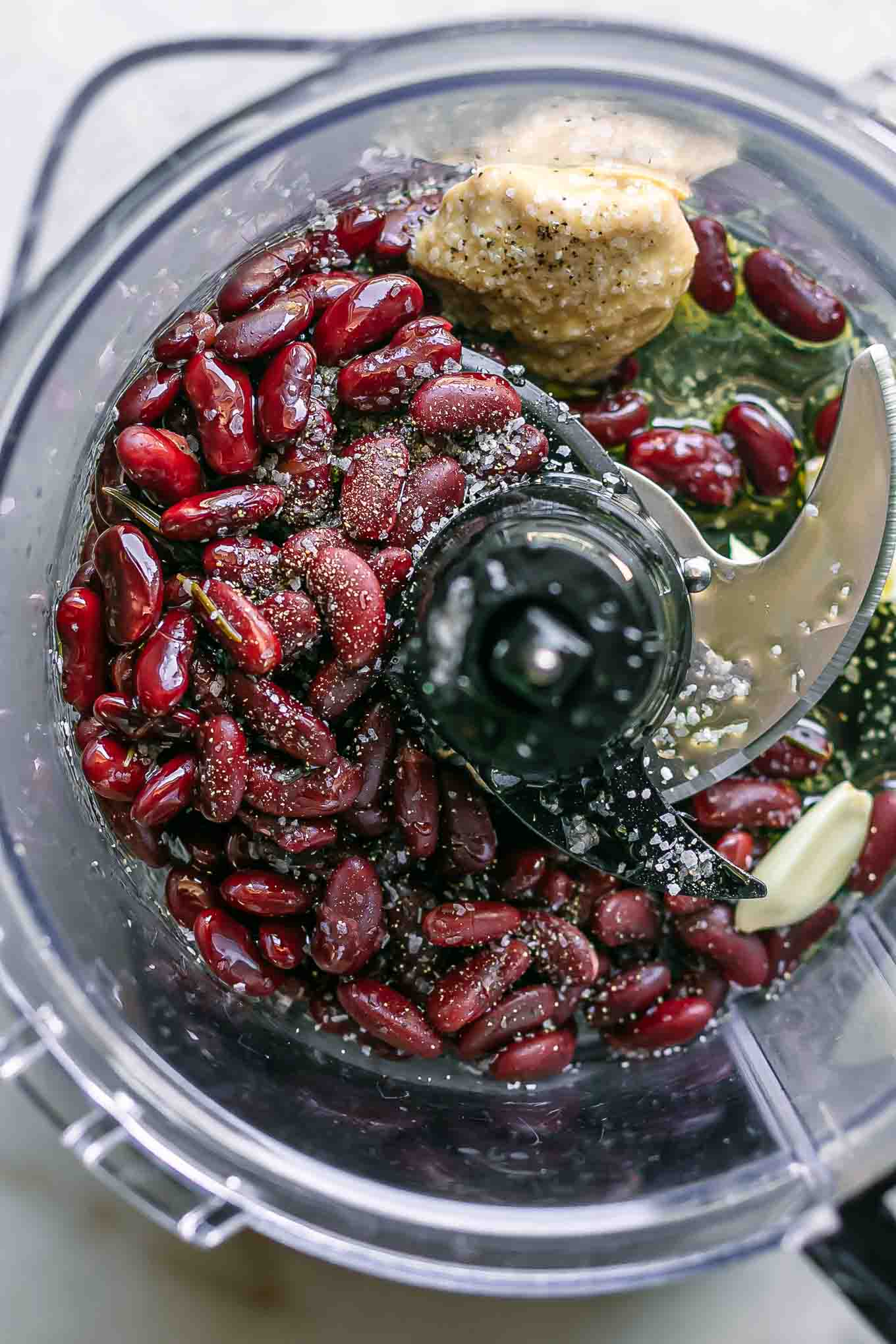 kidney beans, tahini, garlic, and other ingredients for hummus inside a food processor before blending